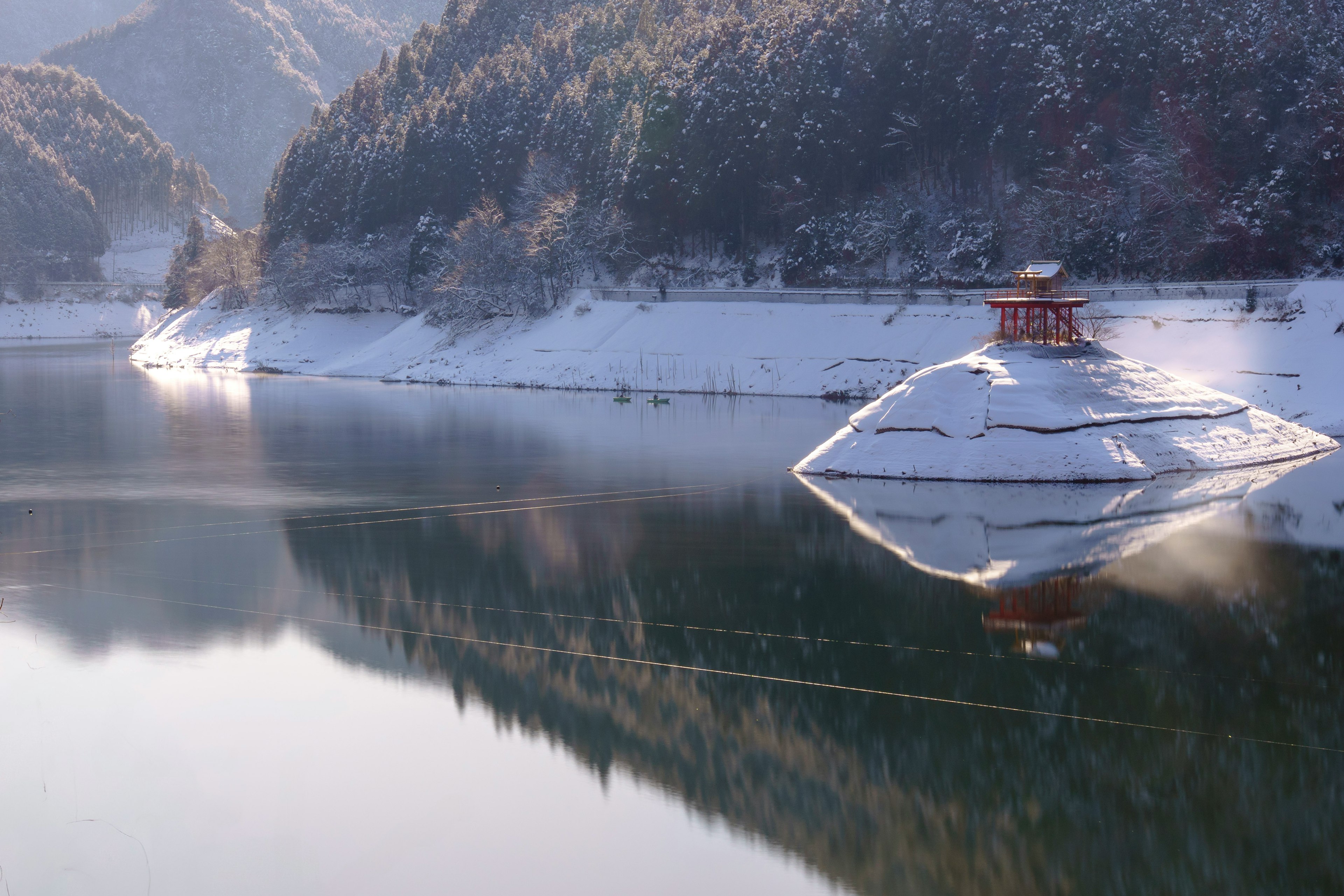 雪に覆われた山々と静かな湖の風景小さな赤い建物が湖のほとりに立っている