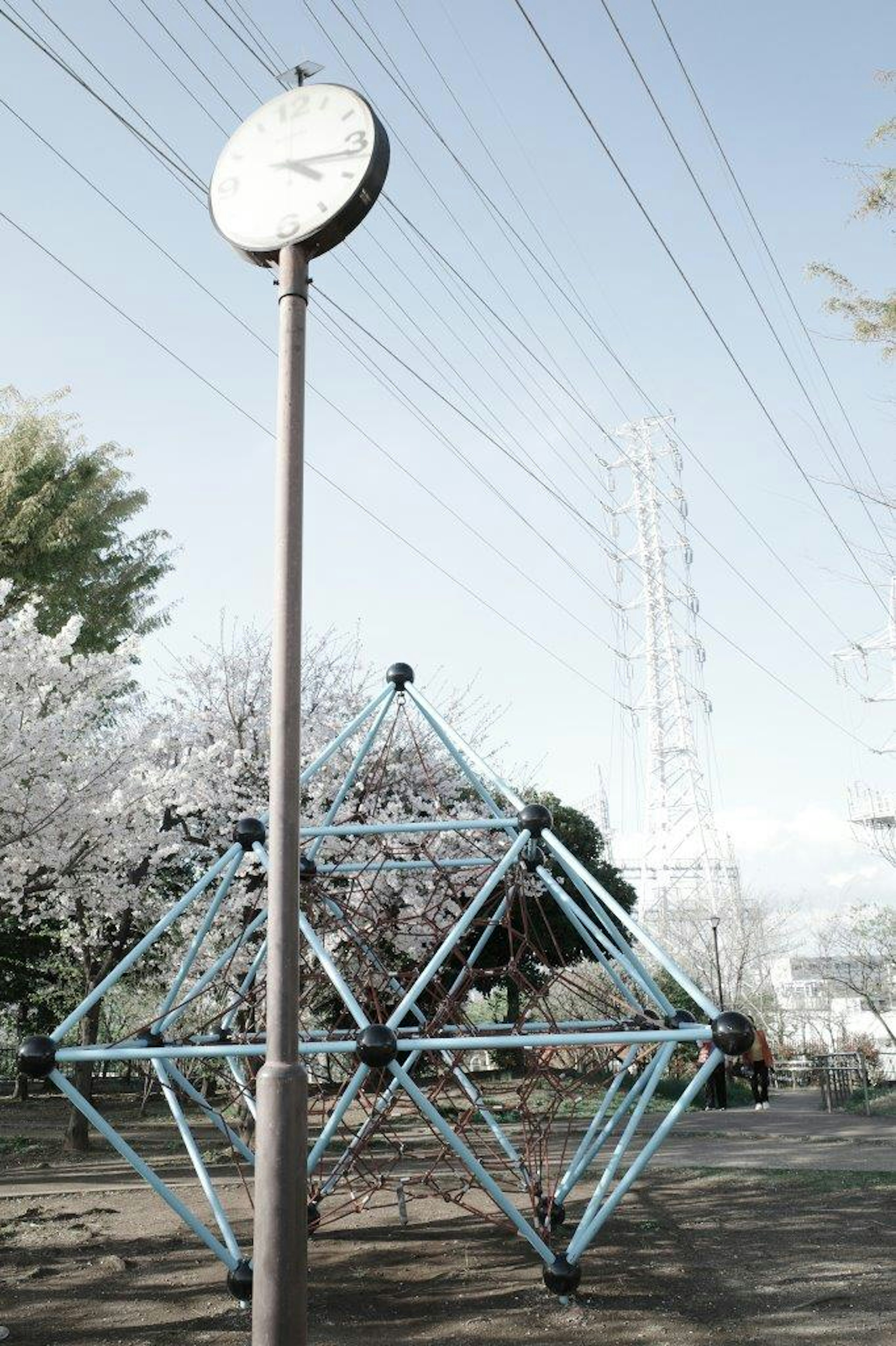 公園の時計と青い遊具が見える風景