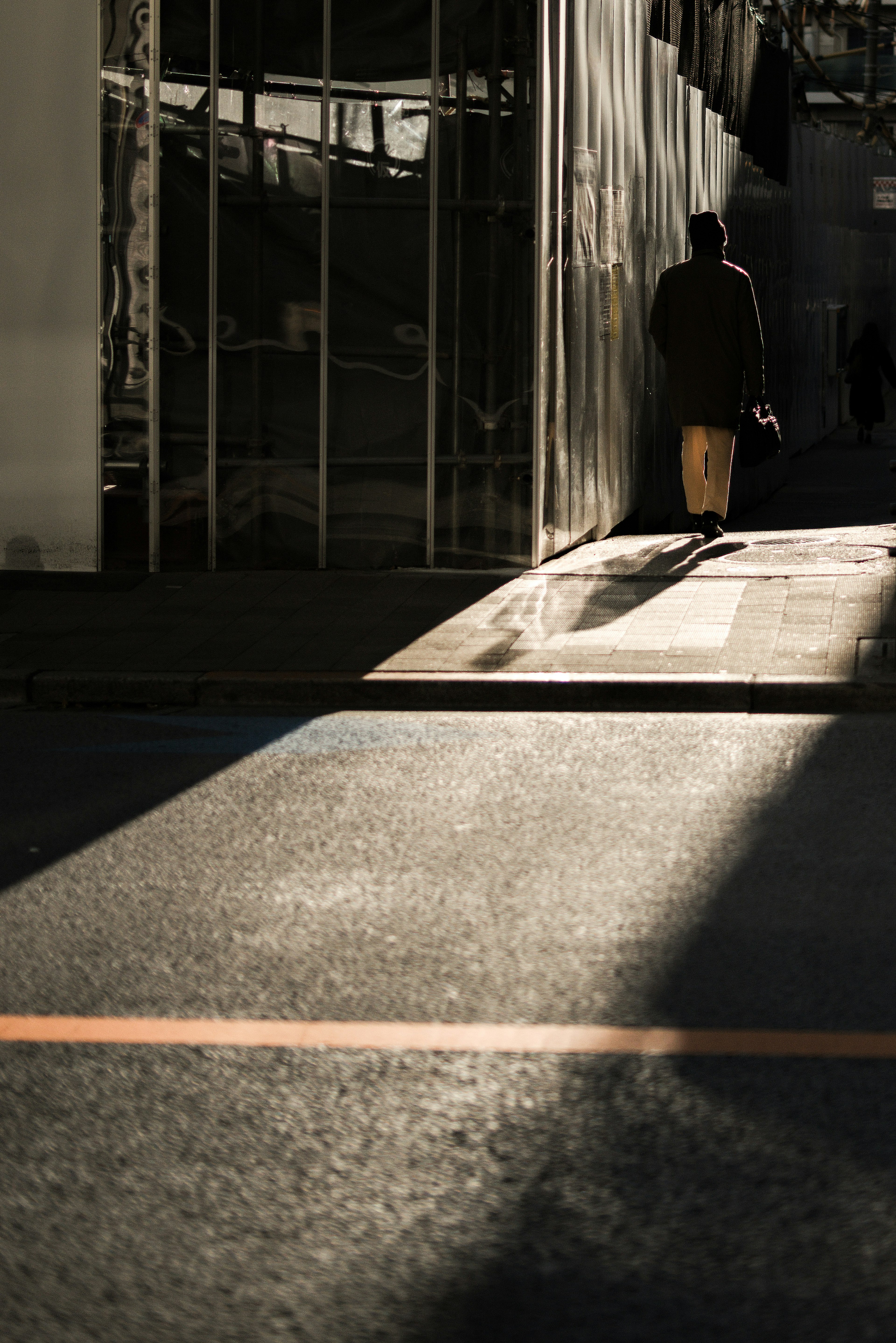 Silhouette di una persona che cammina nel contrasto di luce e ombra