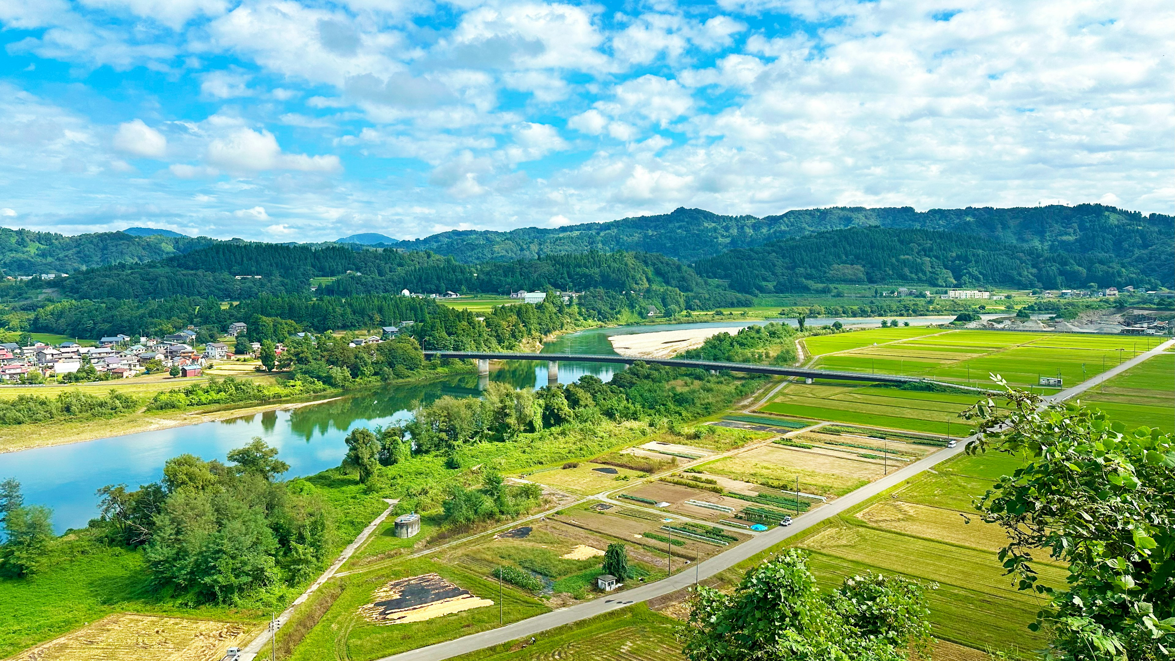 Pemandangan indah sungai dan lahan pertanian subur di bawah langit biru