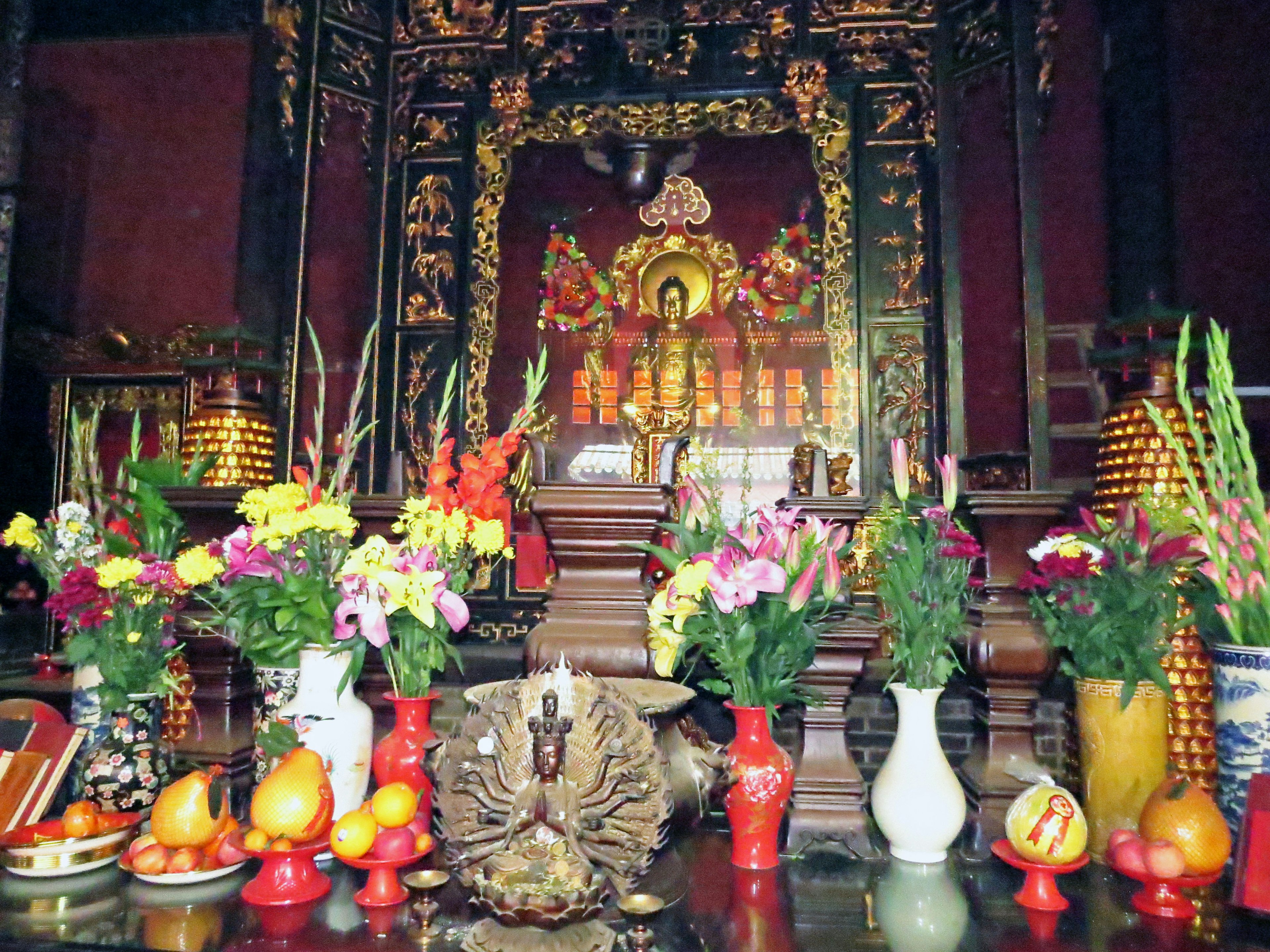 Un autel vibrant avec une statue de Bouddha entourée de fleurs colorées et d'offrandes