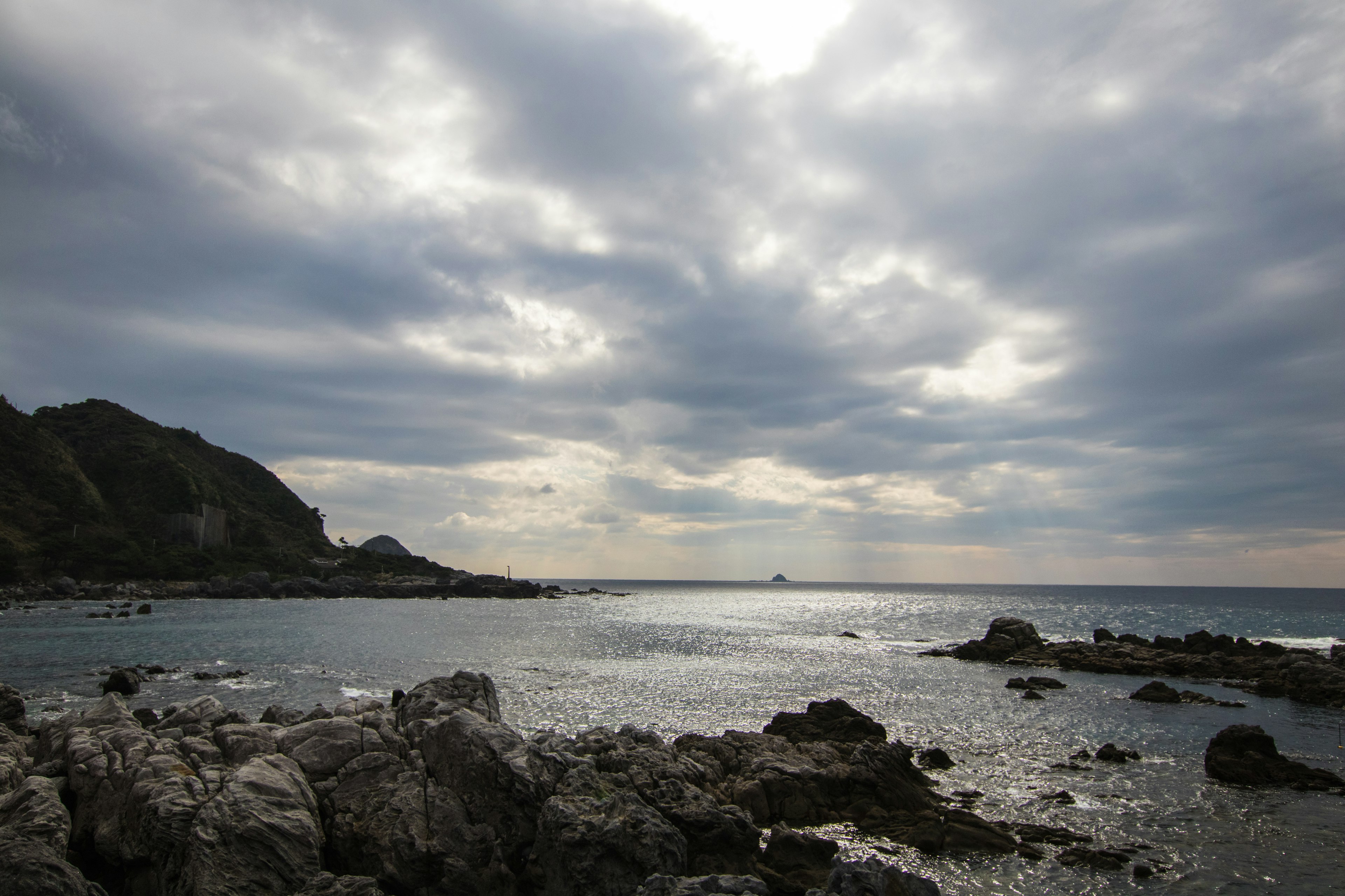 Scena costiera con spiaggia rocciosa e nuvole drammatiche