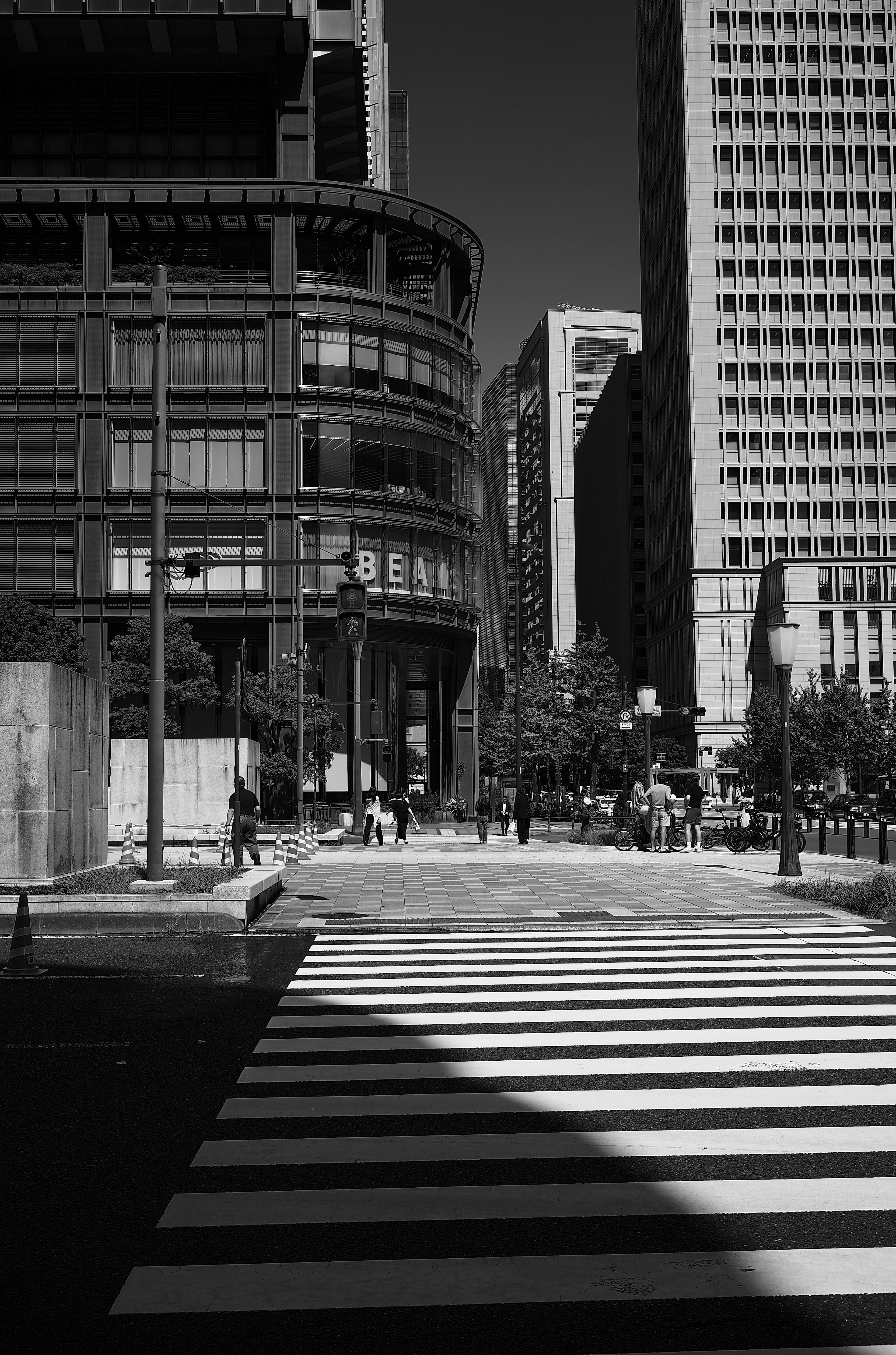 Scène urbaine en noir et blanc avec un passage piéton et des bâtiments modernes