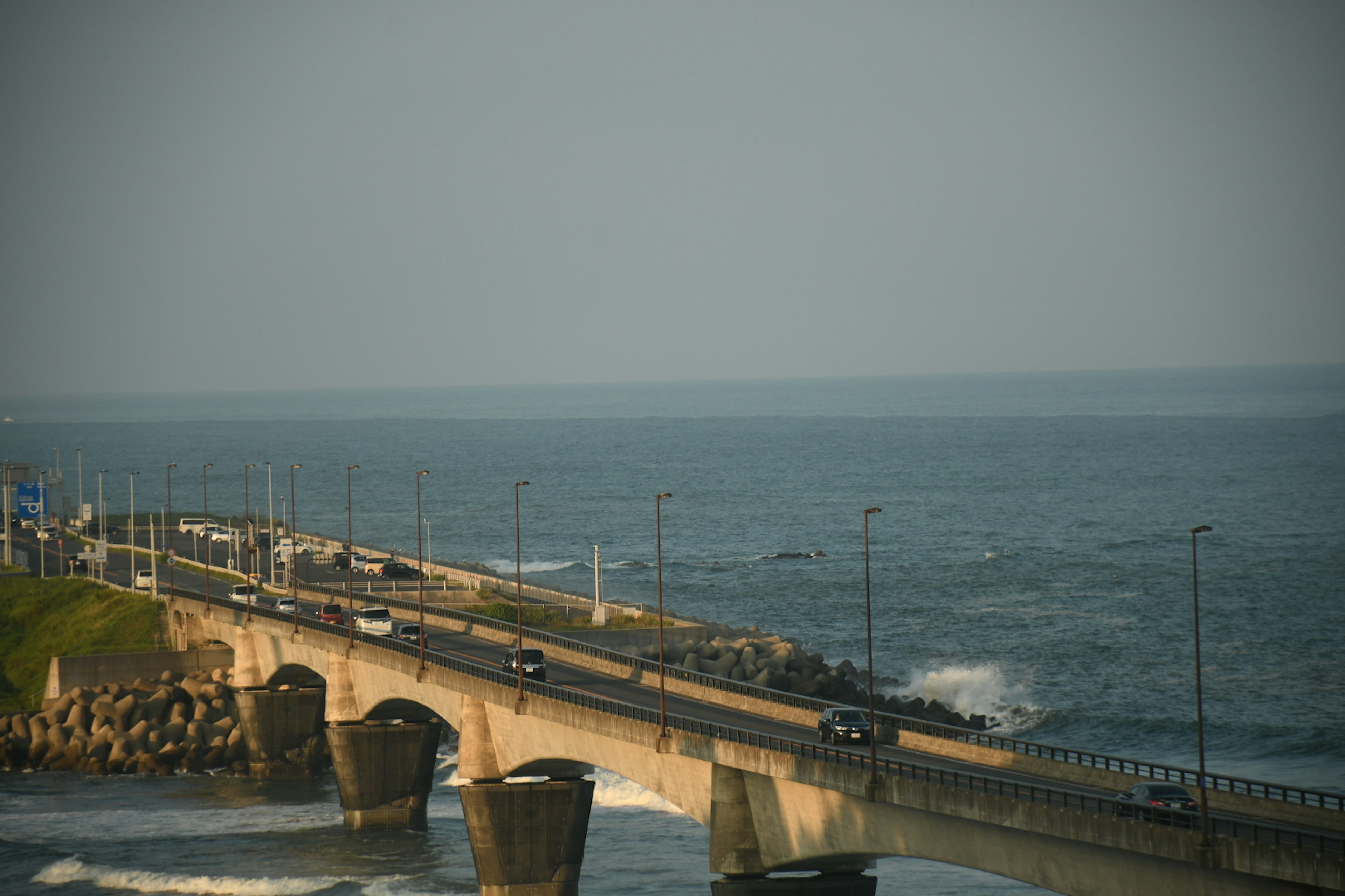 面向海洋的桥的风景，道路上有汽车和拍打的海浪