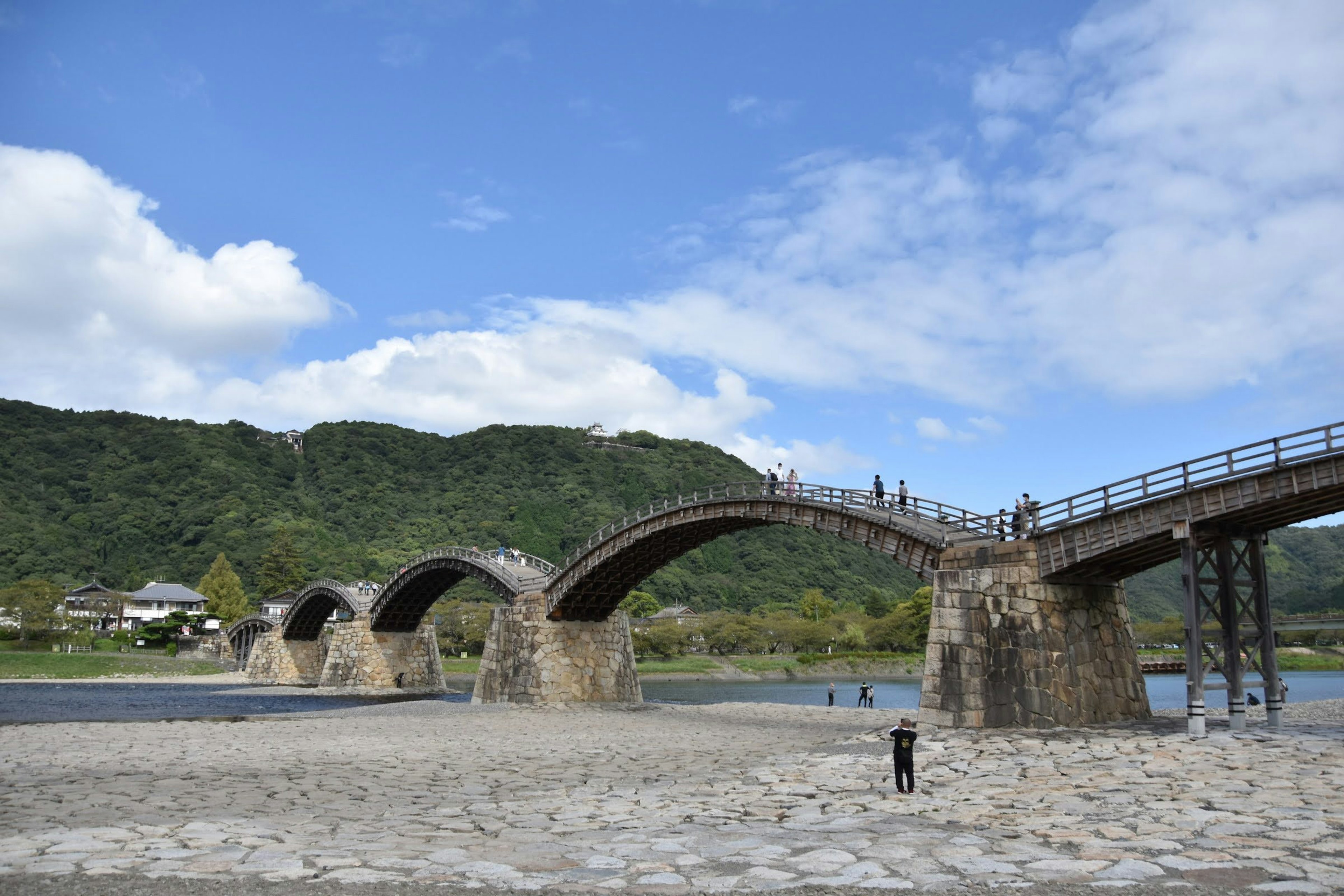 Hermoso puente arqueado con montañas y río al fondo