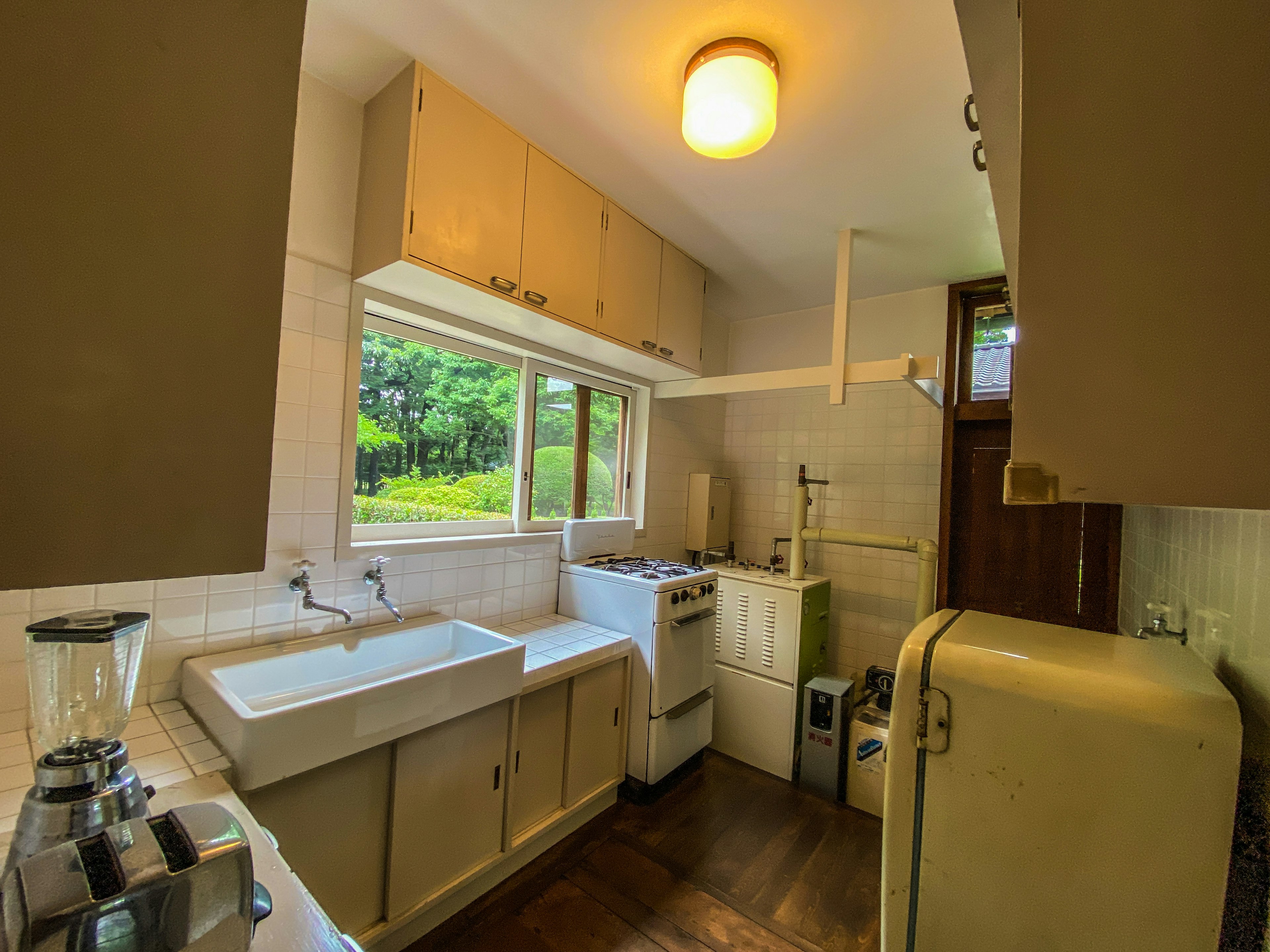 Bright kitchen interior with natural light from window simple cabinets vintage refrigerator sink and washing machine