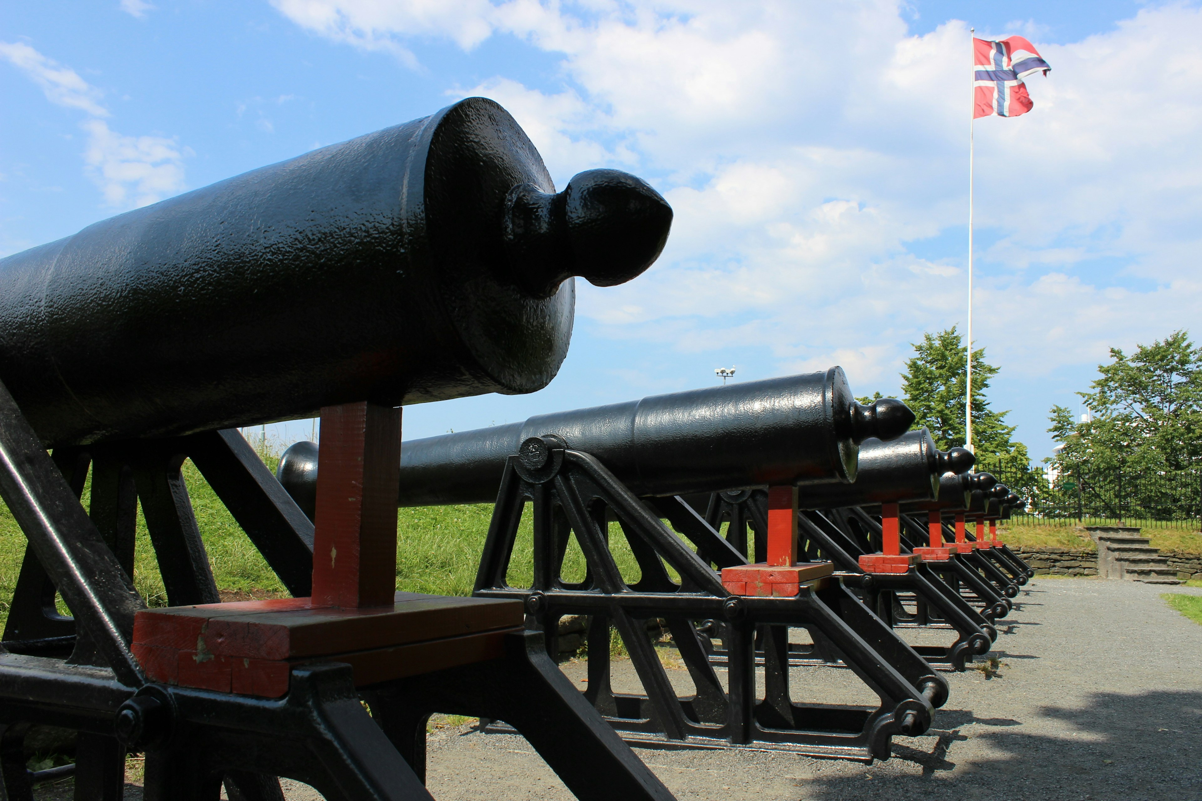 Row of black cannons with a flag in the background and blue sky