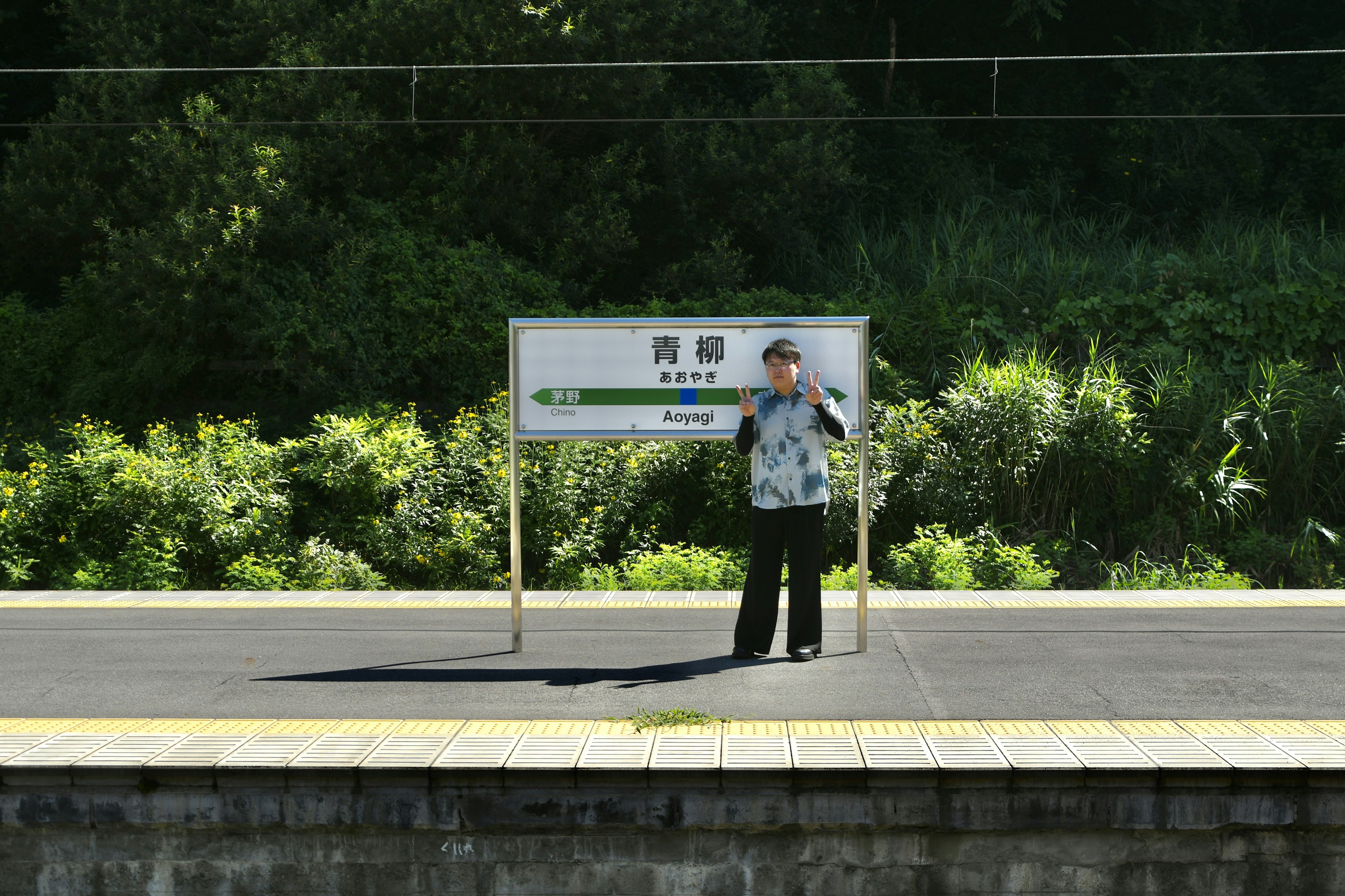 Person steht auf einem Bahnsteig neben einem Schild