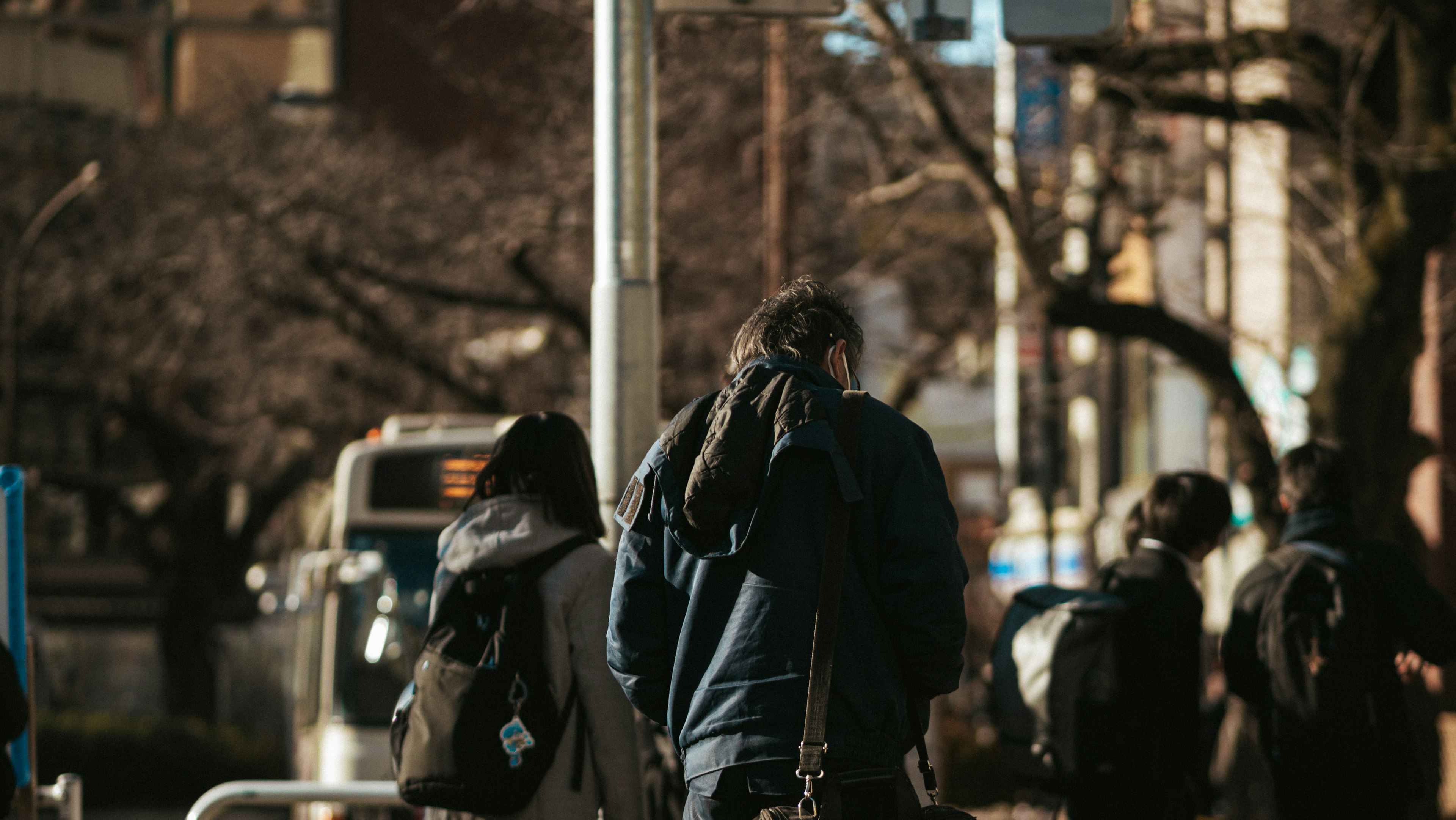 Escena urbana con personas caminando destacando a un hombre de espaldas