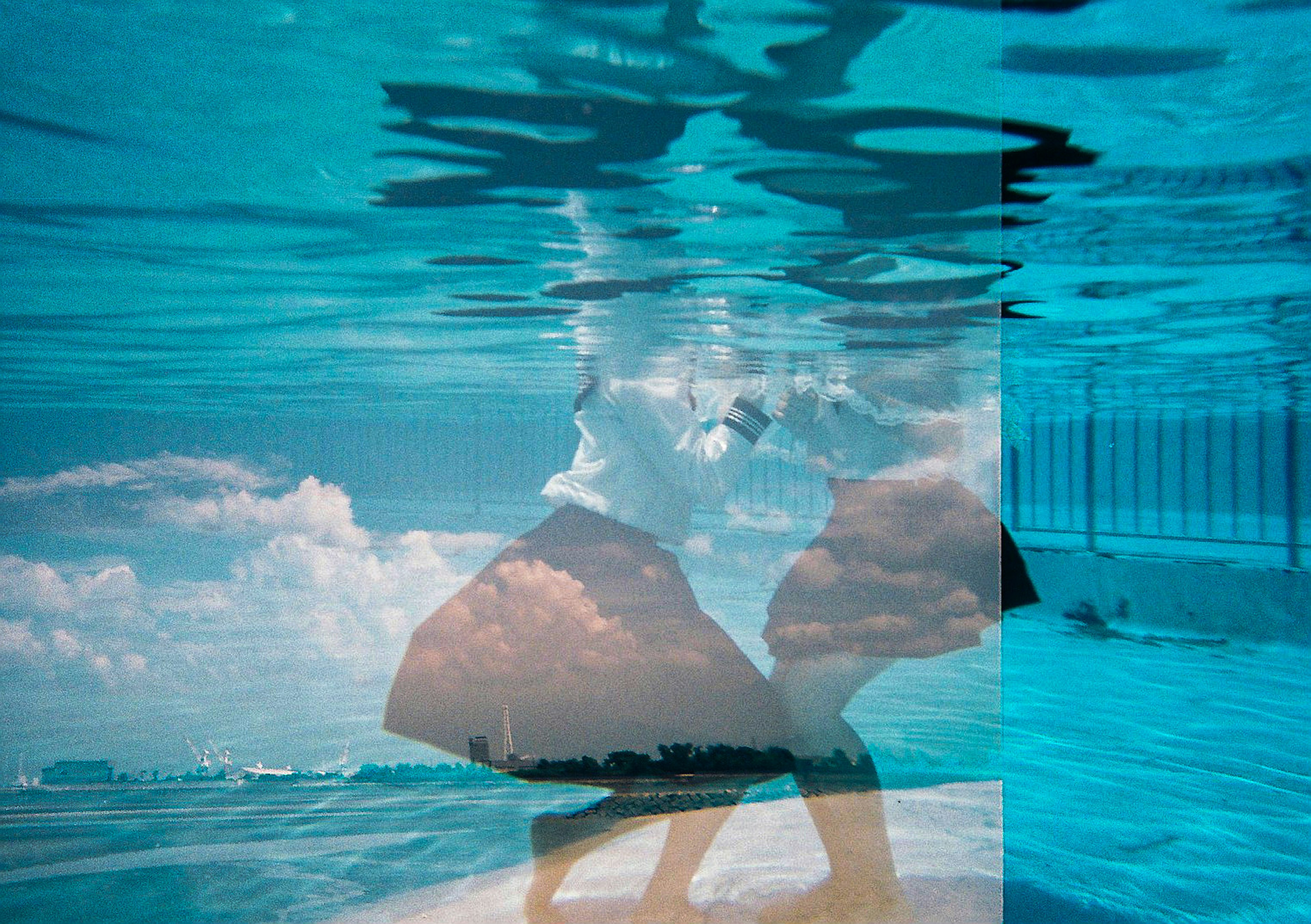 Silhouette of a couple dancing underwater with reflections on the blue surface