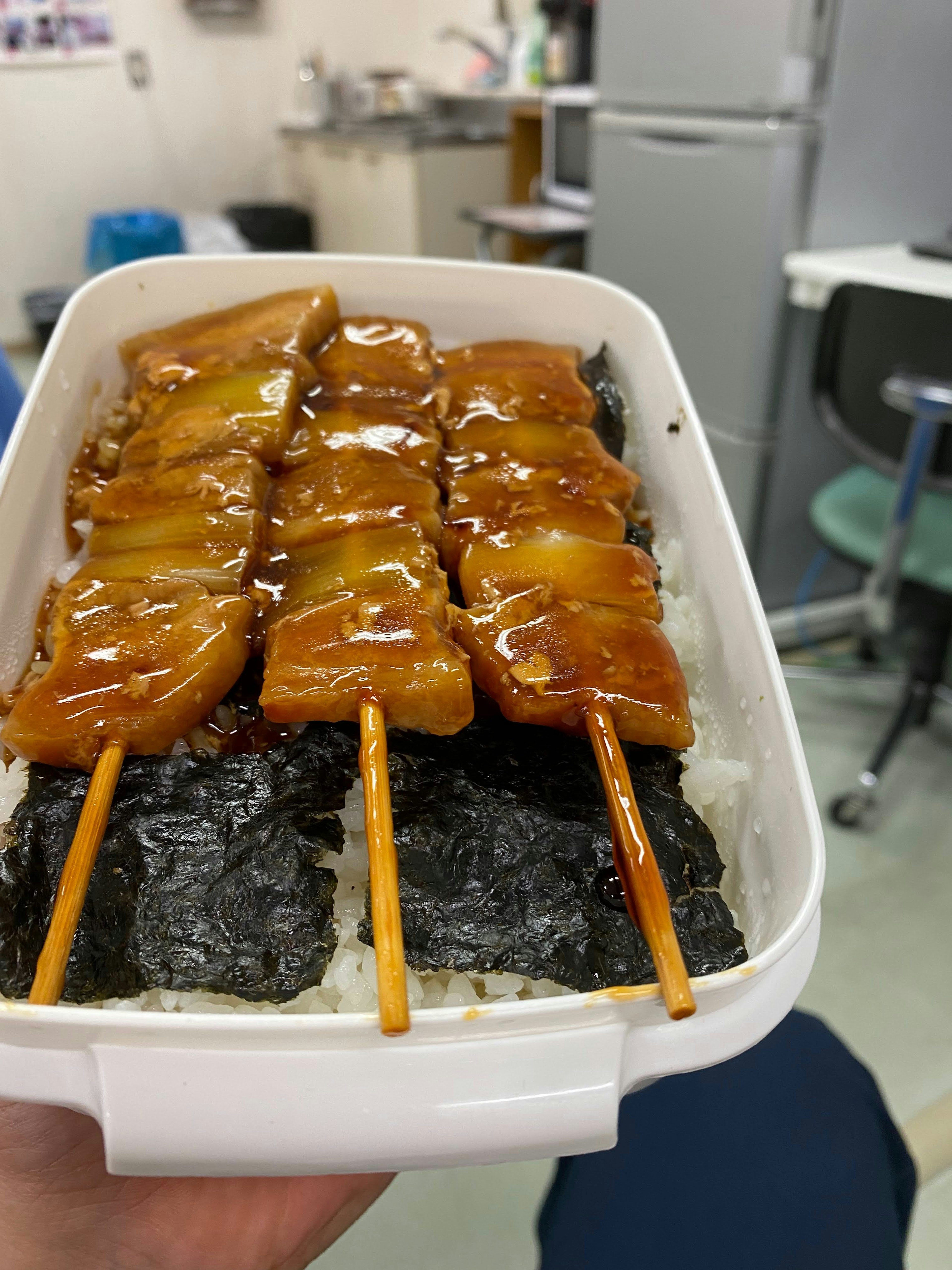 Brochettes de poulet grillées sur du riz dans une boîte à bento blanche