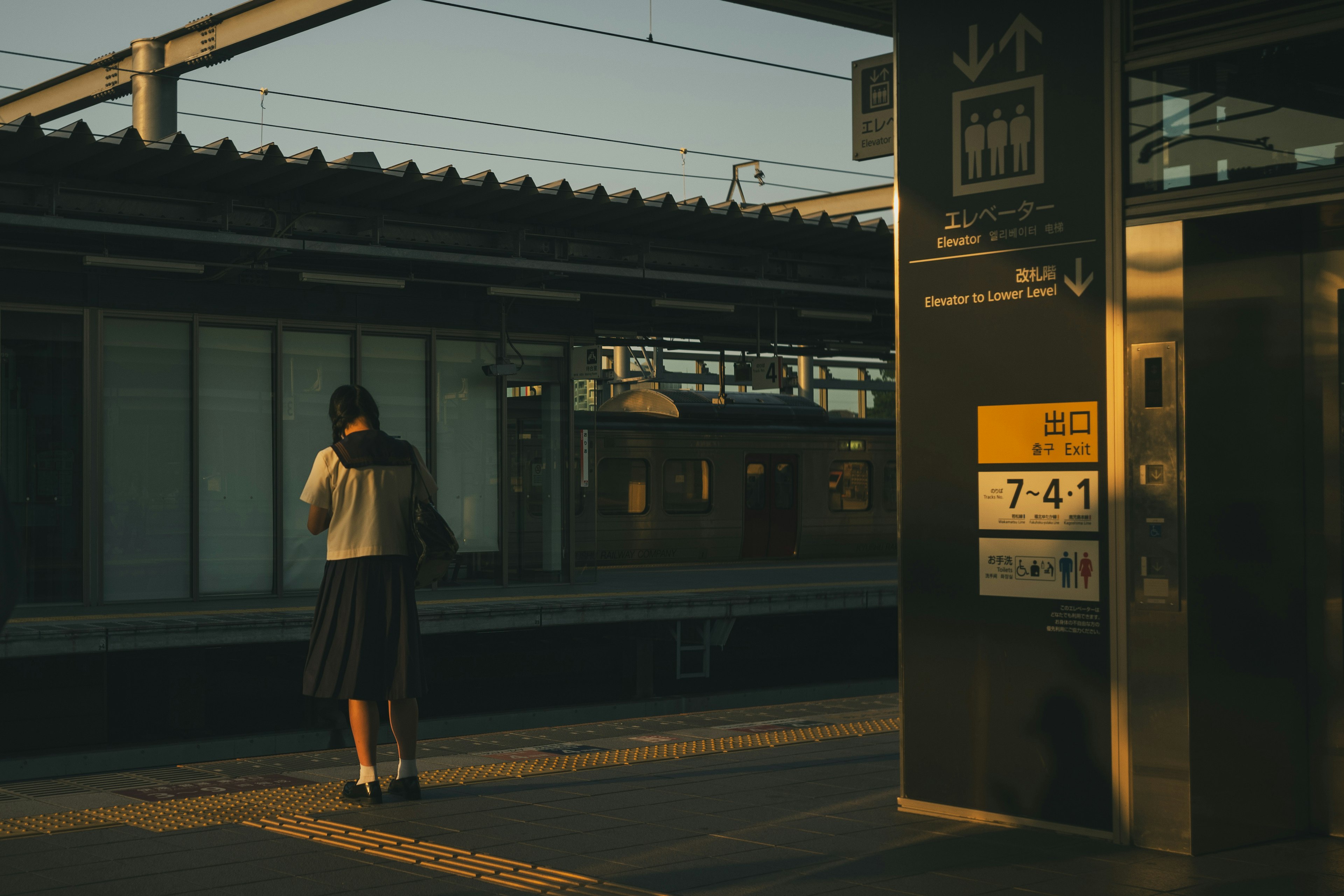 駅のプラットフォームで待つ女性夕日が当たる