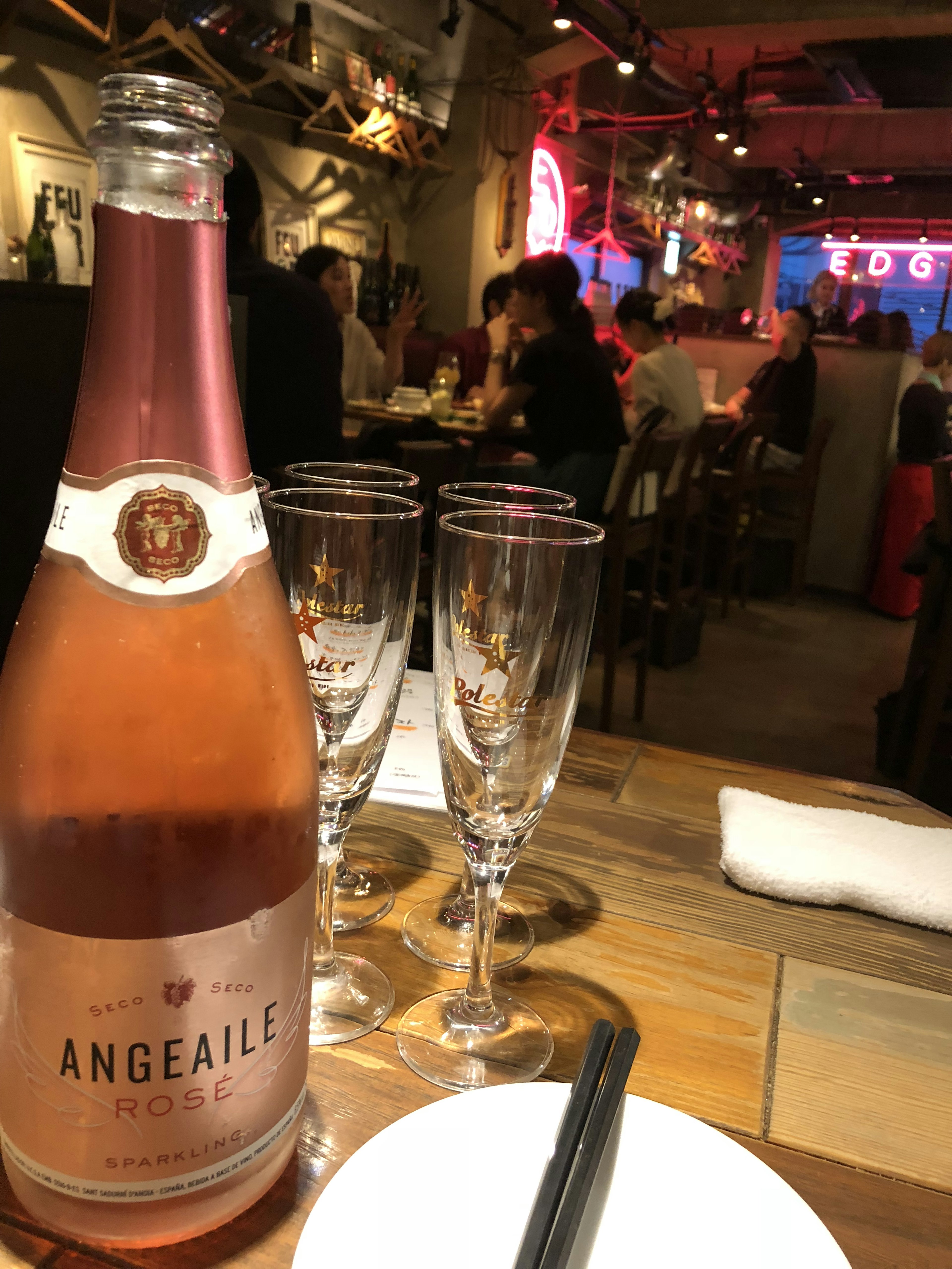 A bottle of rose wine and champagne glasses on a table in a restaurant setting