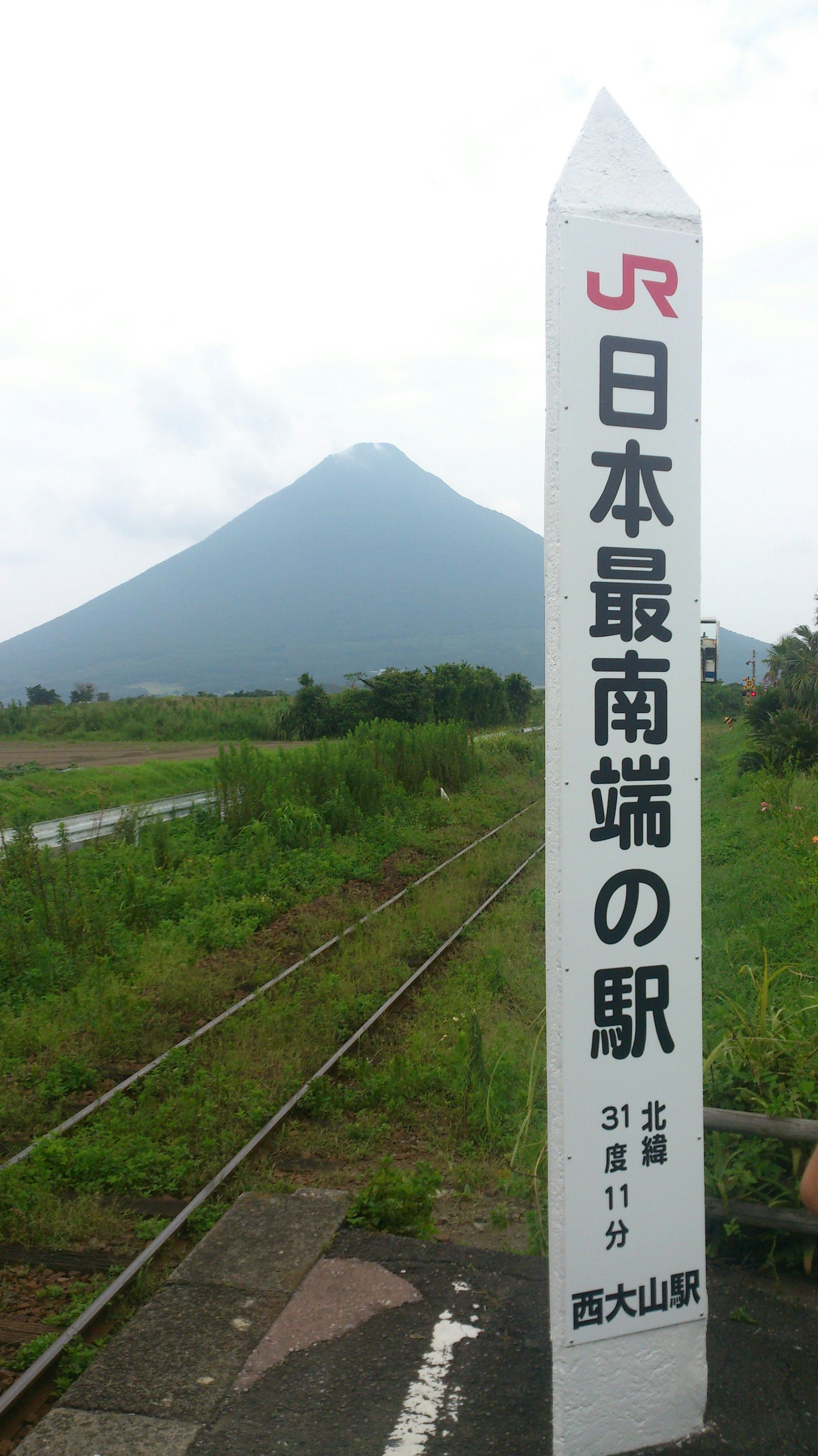 Señal de la estación más al sur de Japón con fondo montañoso