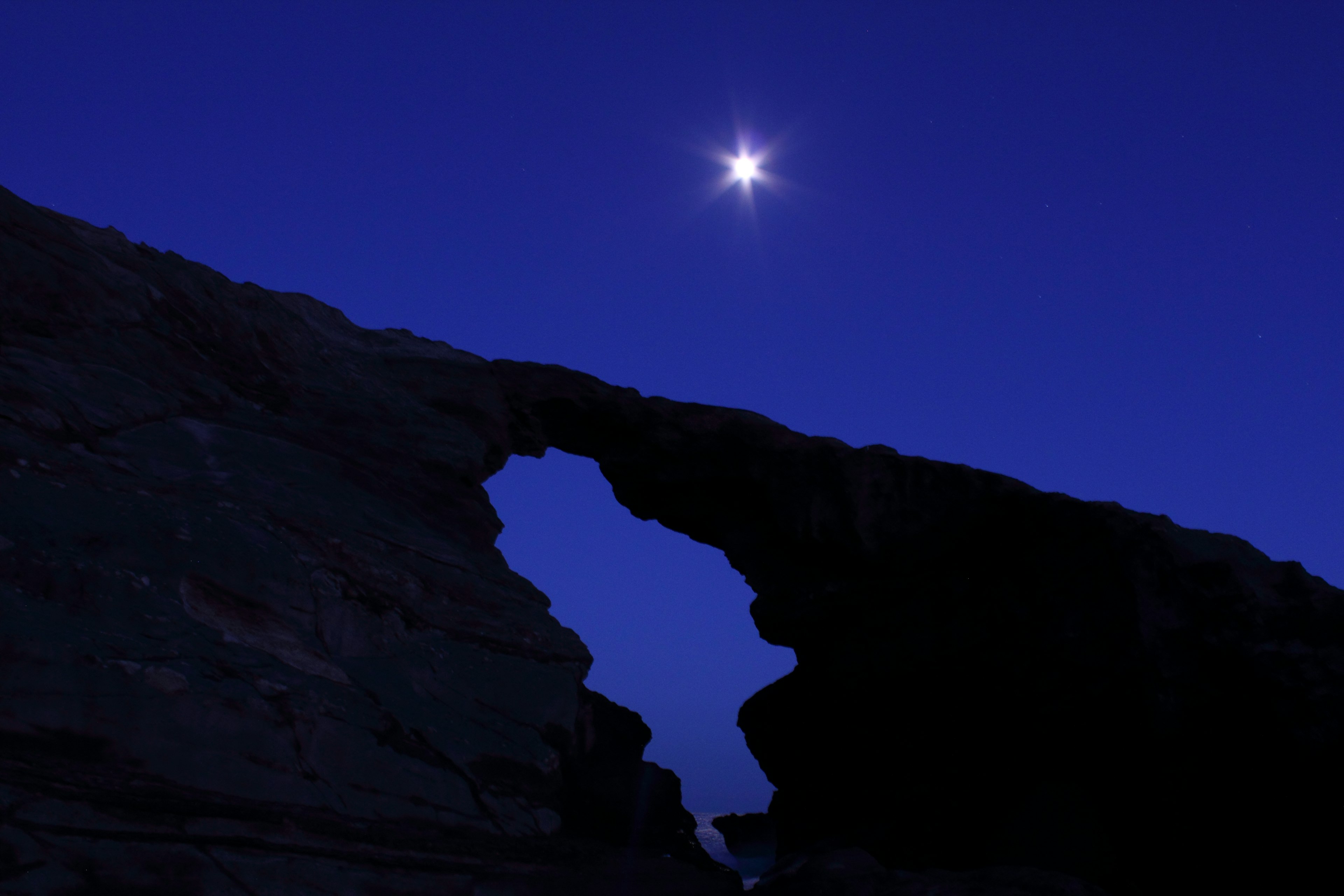 Estrella brillando en el cielo nocturno sobre un arco de roca