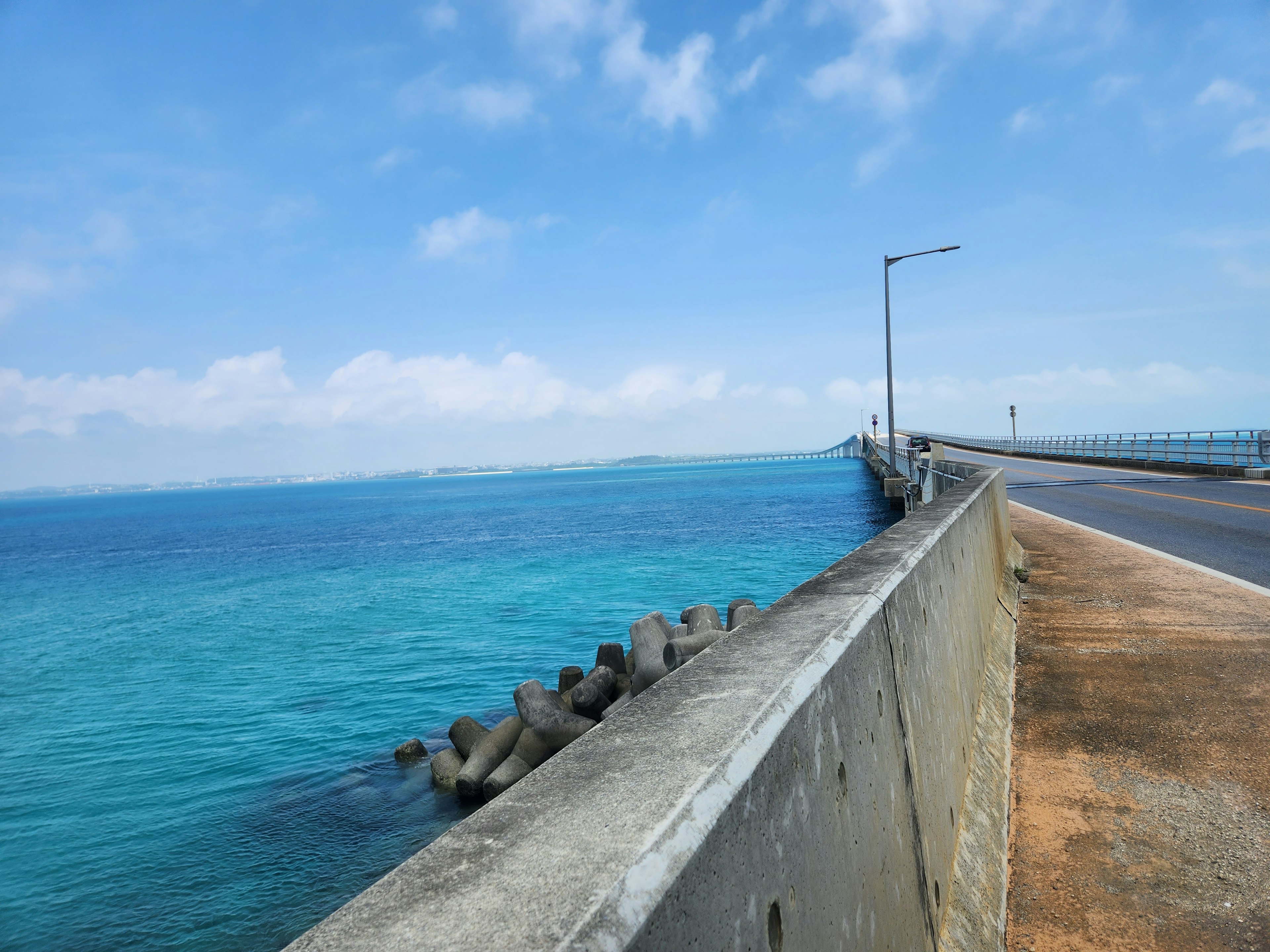 Jalan pesisir dengan air biru jernih dan langit cerah