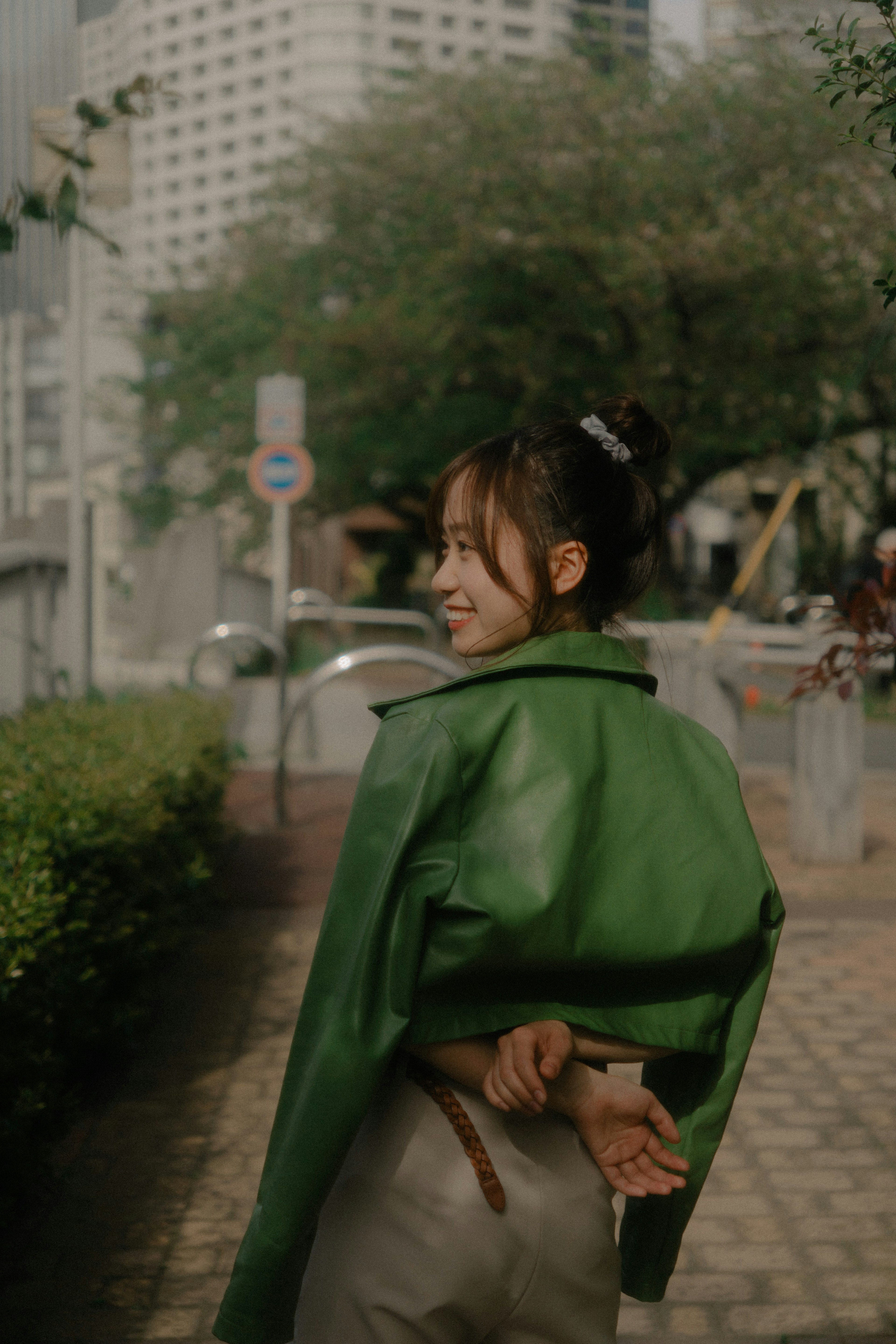 Woman wearing a green jacket looking back in an urban setting