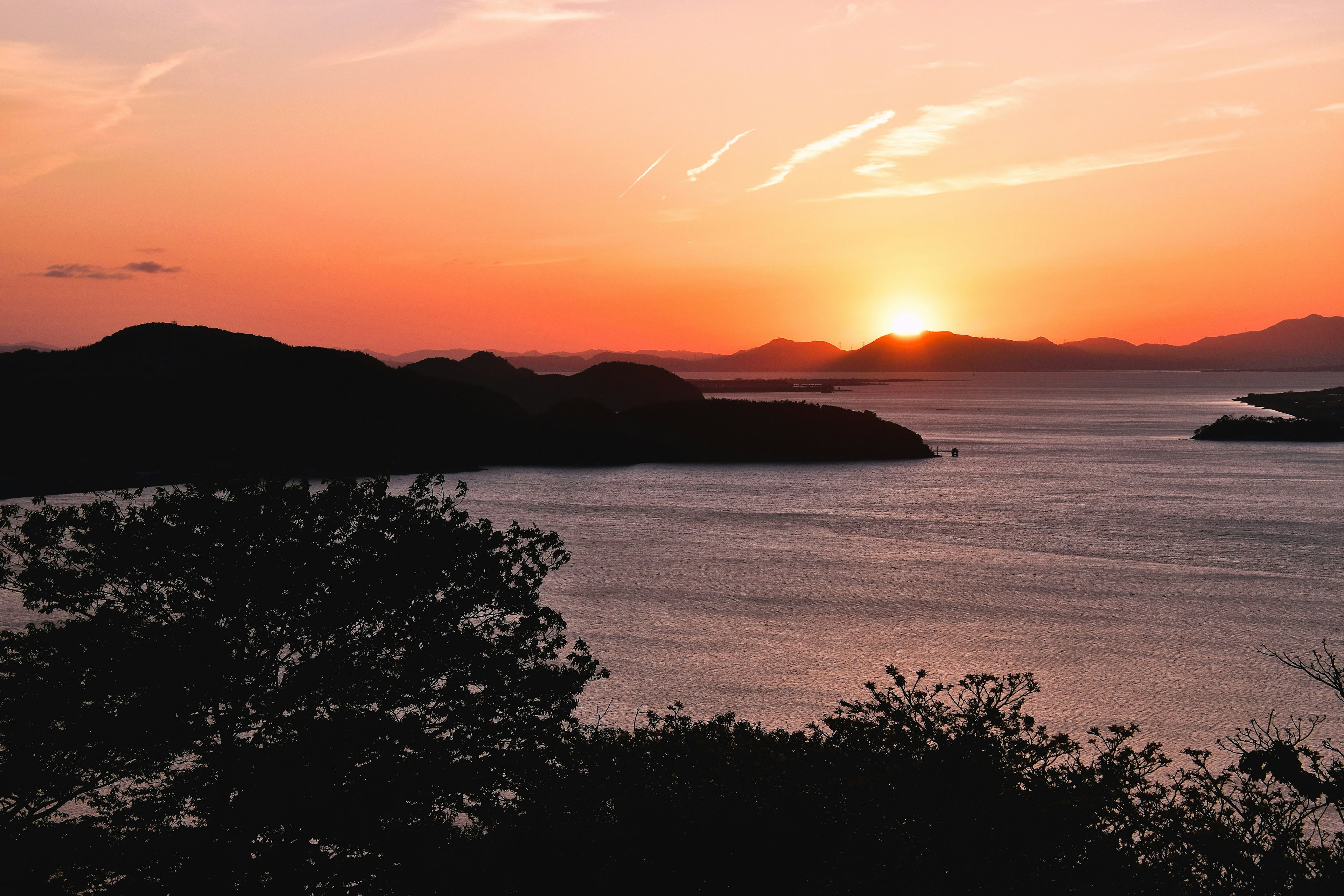 Sunset over the sea with silhouetted hills