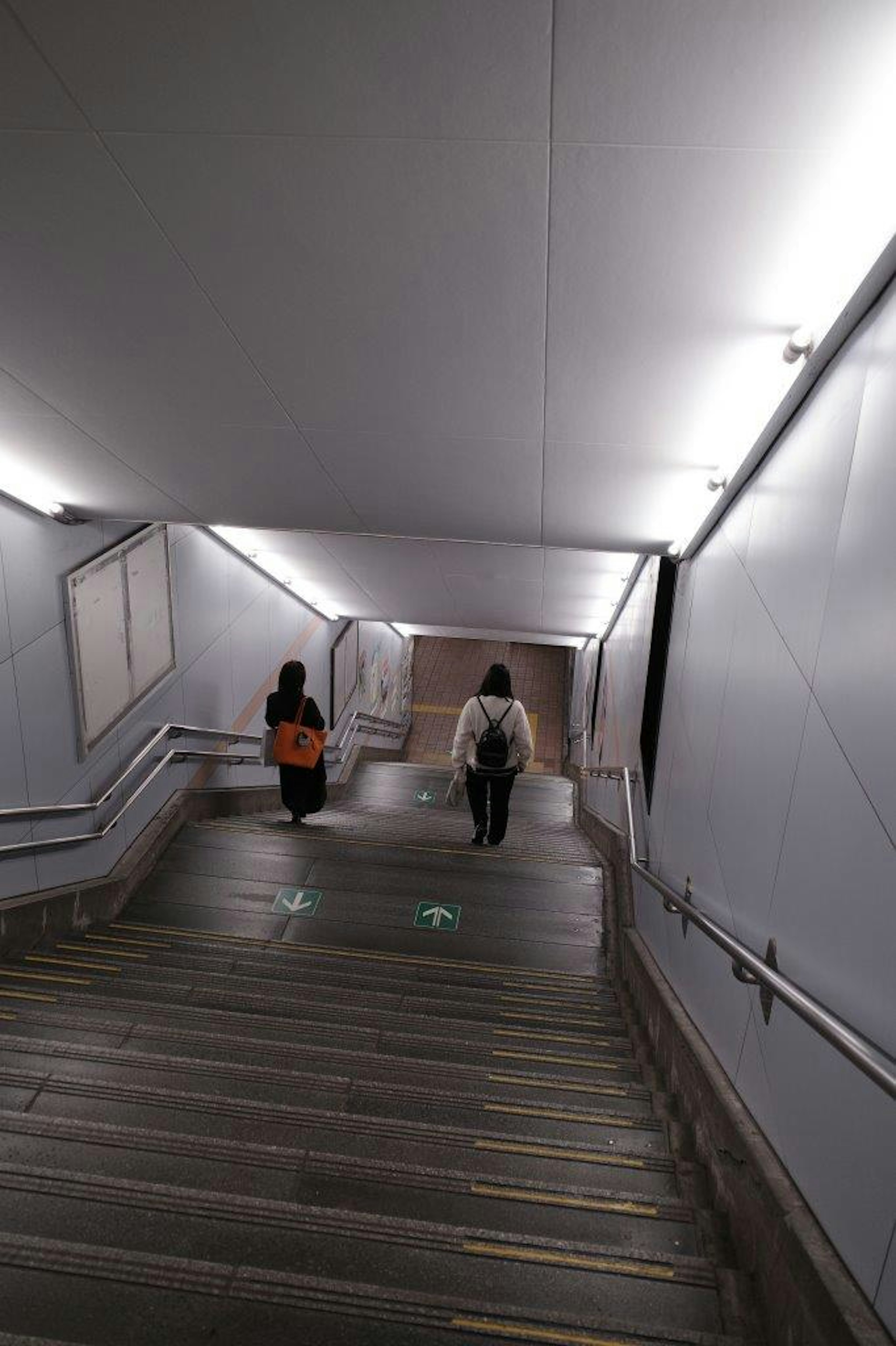 Two people walking down a staircase with bright lighting