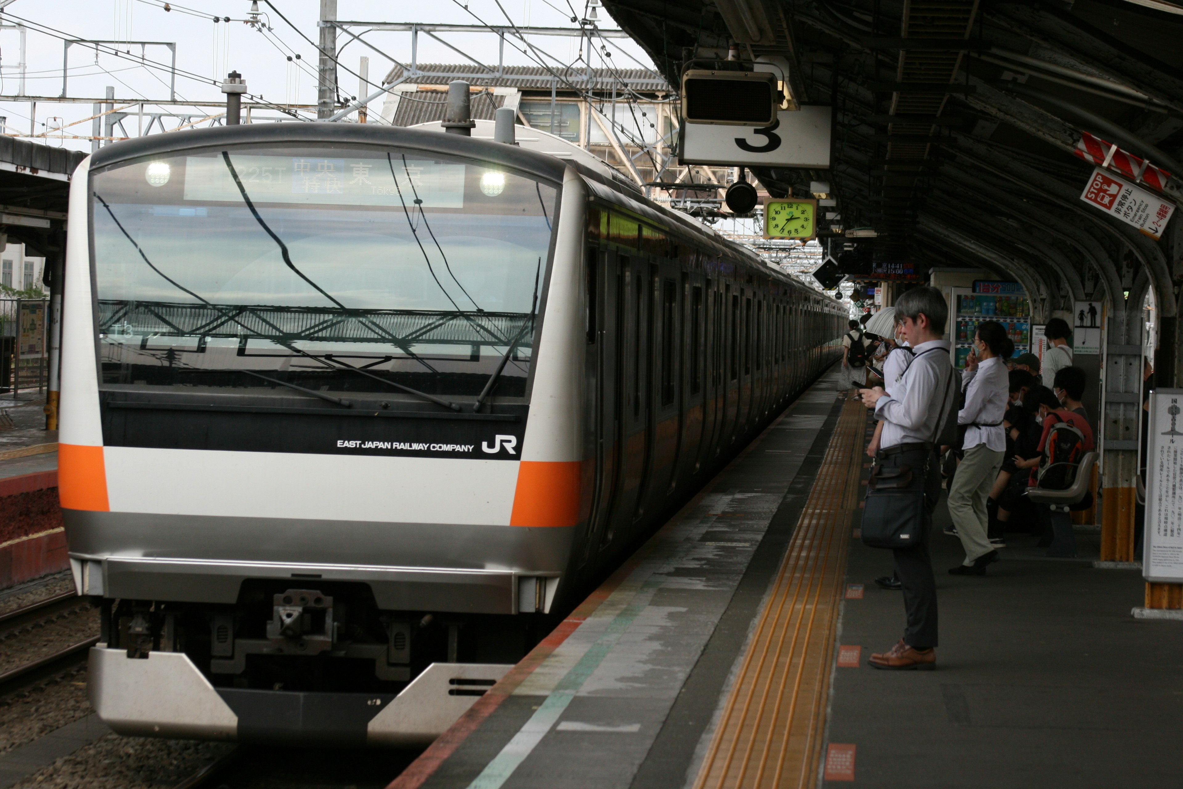 A train is stopped at a station with a man waiting