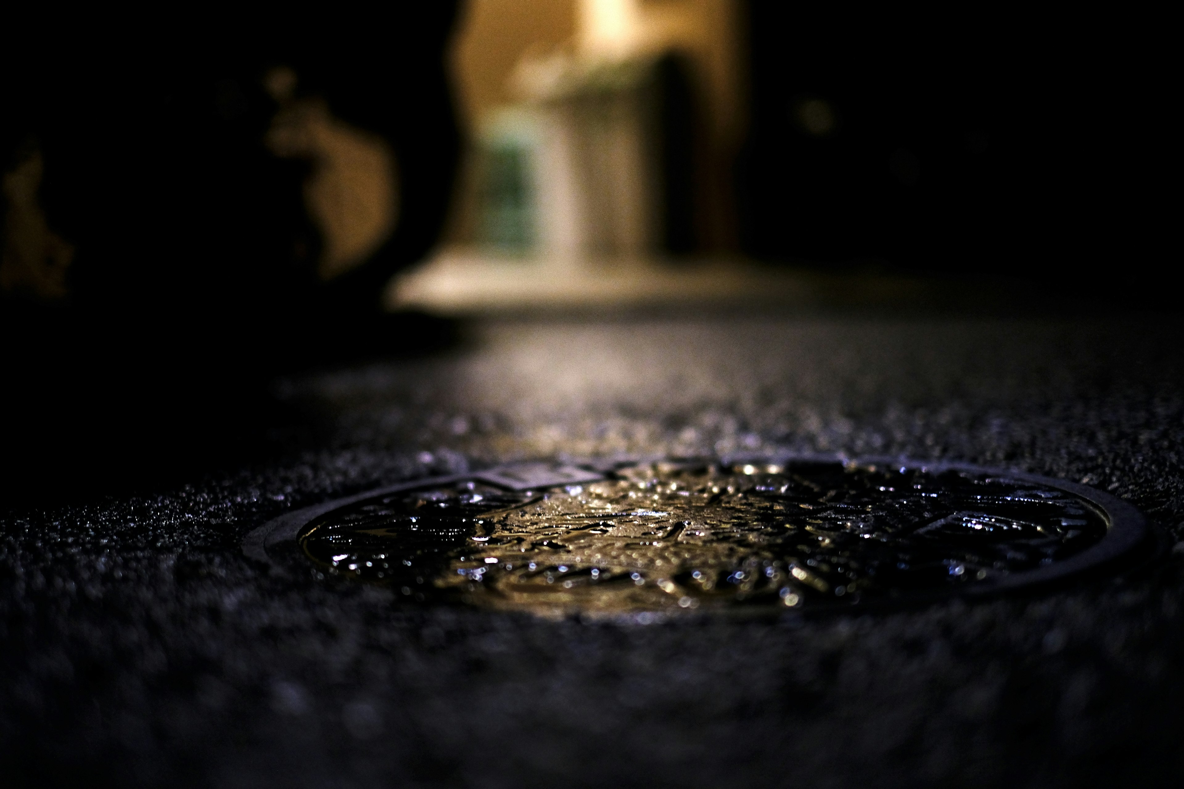 Close-up of a manhole cover with water droplets in a dark background