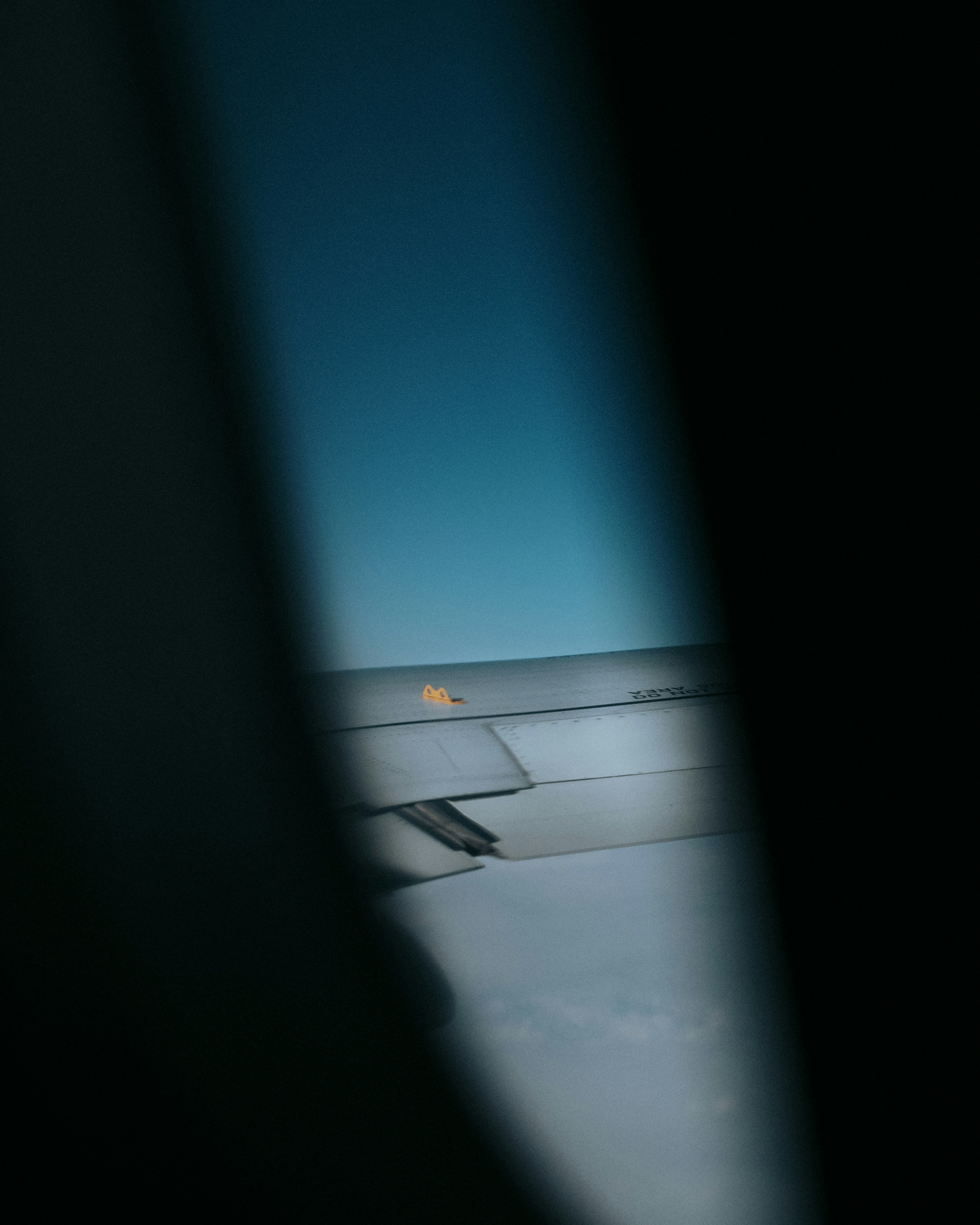 Blick auf den Flugzeugflügel und den blauen Himmel aus einem Fenster