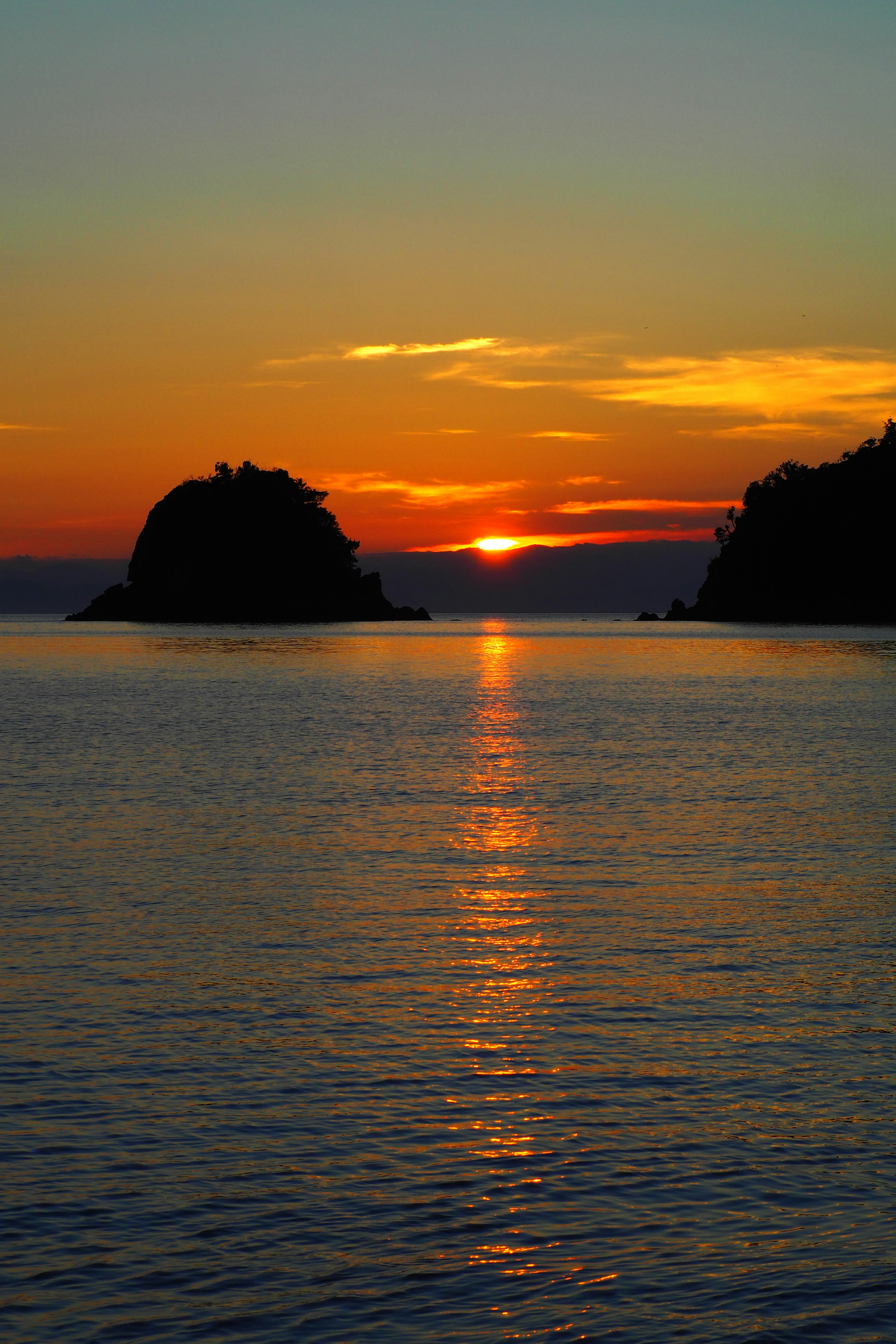 夕日が海に沈む風景 黒い島と水面に映る光