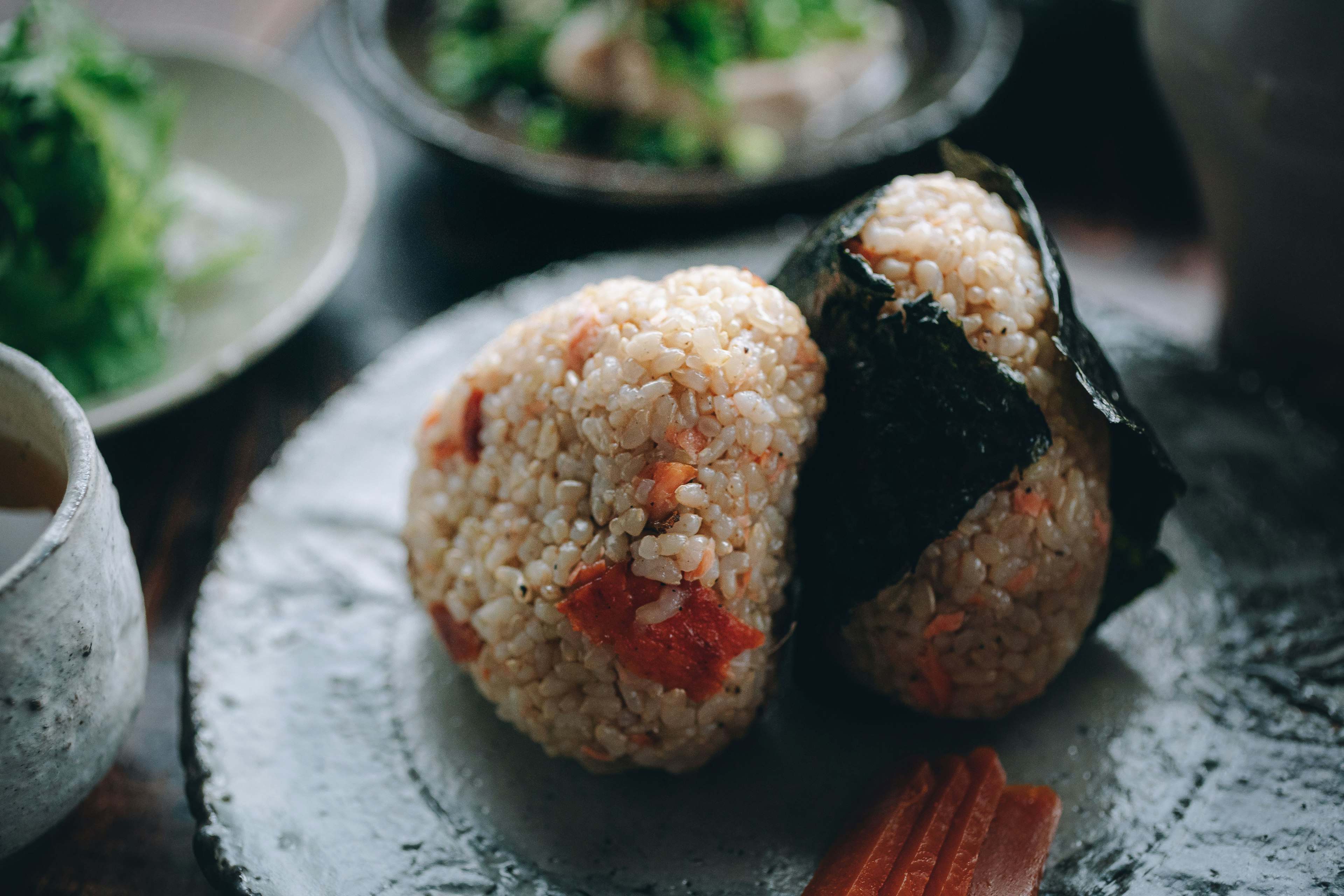 Two rice balls with seaweed on a textured plate