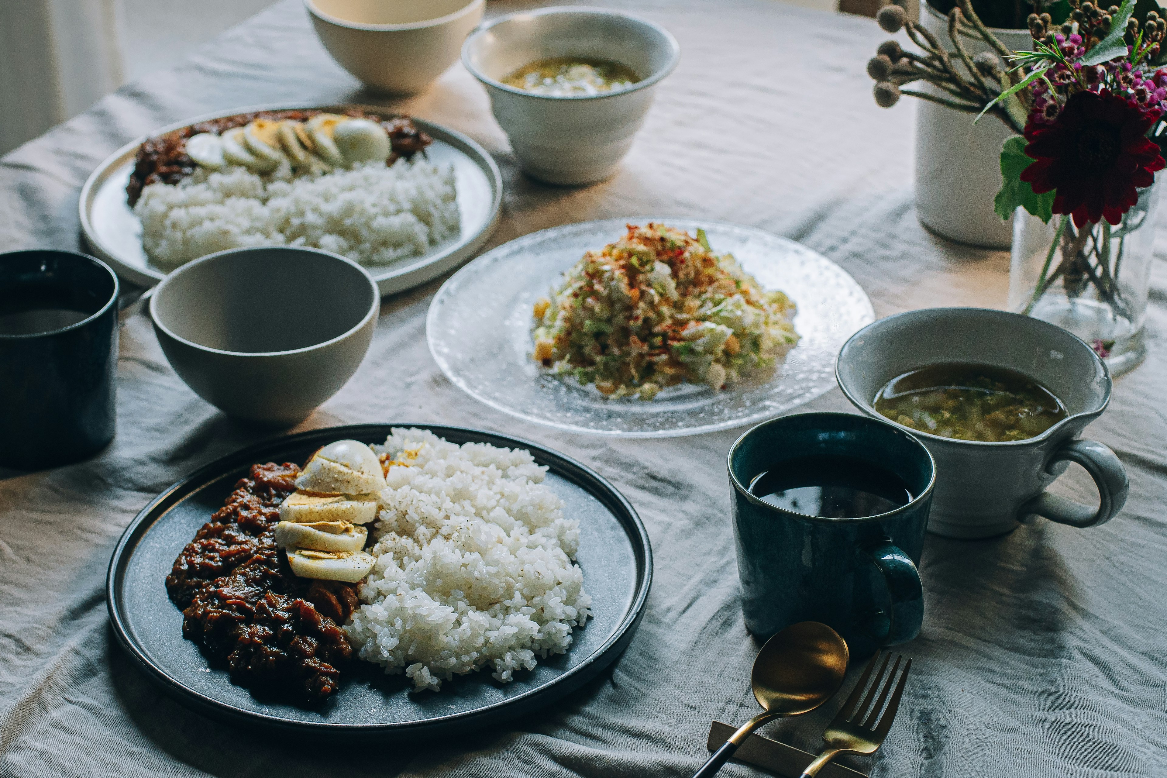 식탁에 놓인 밥, 고기 요리, 샐러드, 수프, 꽃 장식이 있는 모습