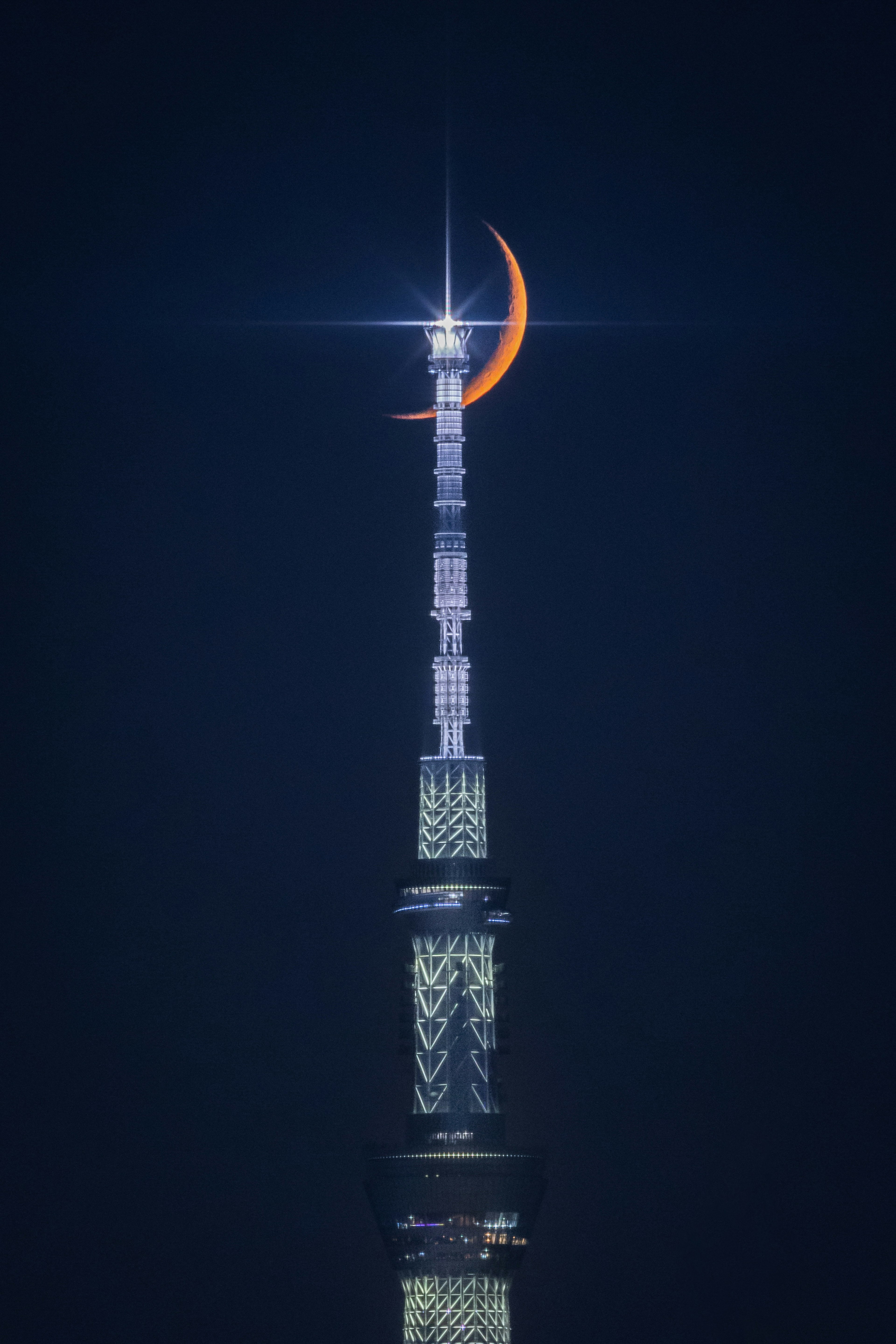 Silhouette de una luna creciente en la cima de Tokyo Skytree con una estrella brillante