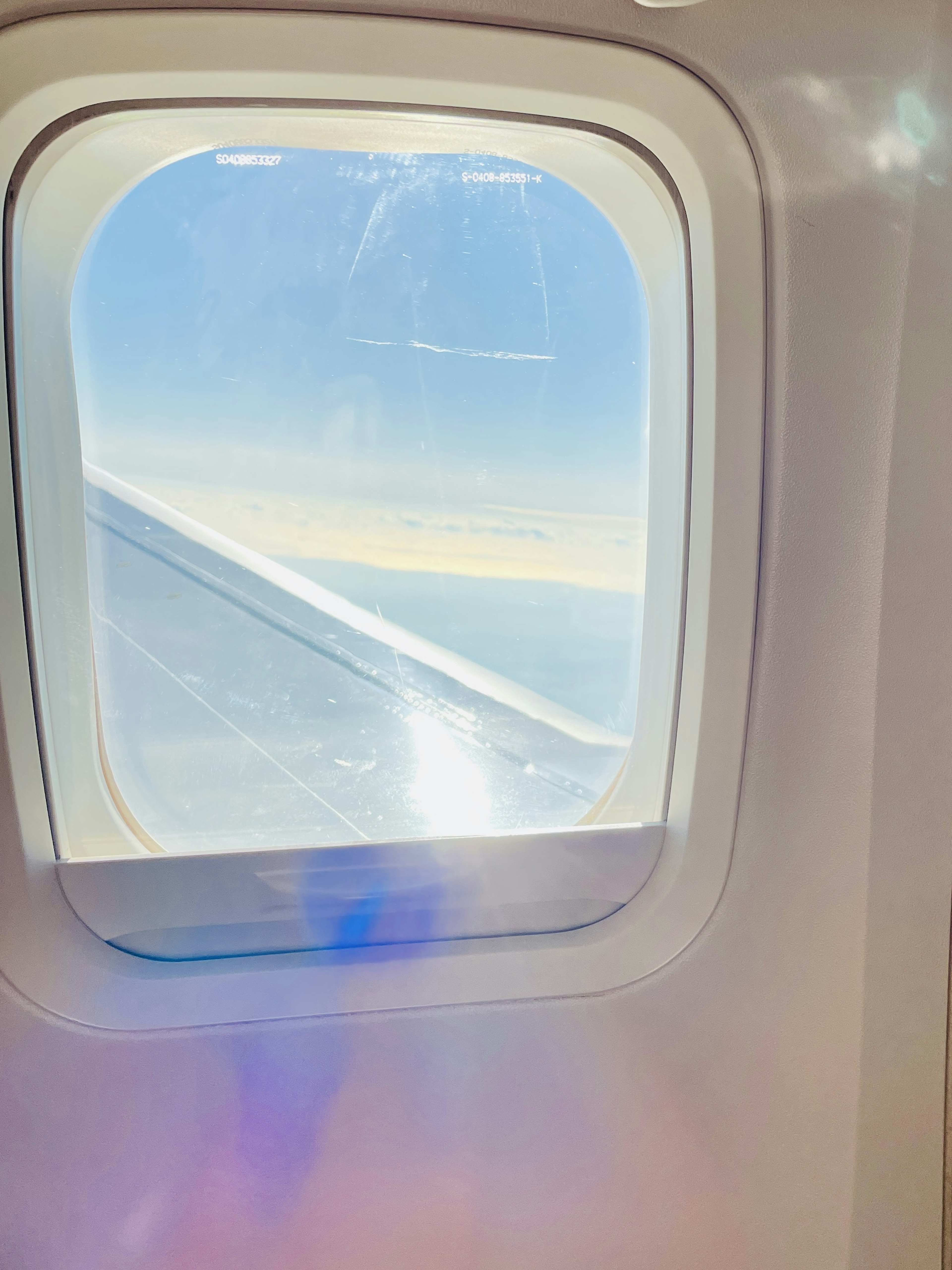 View of the blue sky and wing from an airplane window