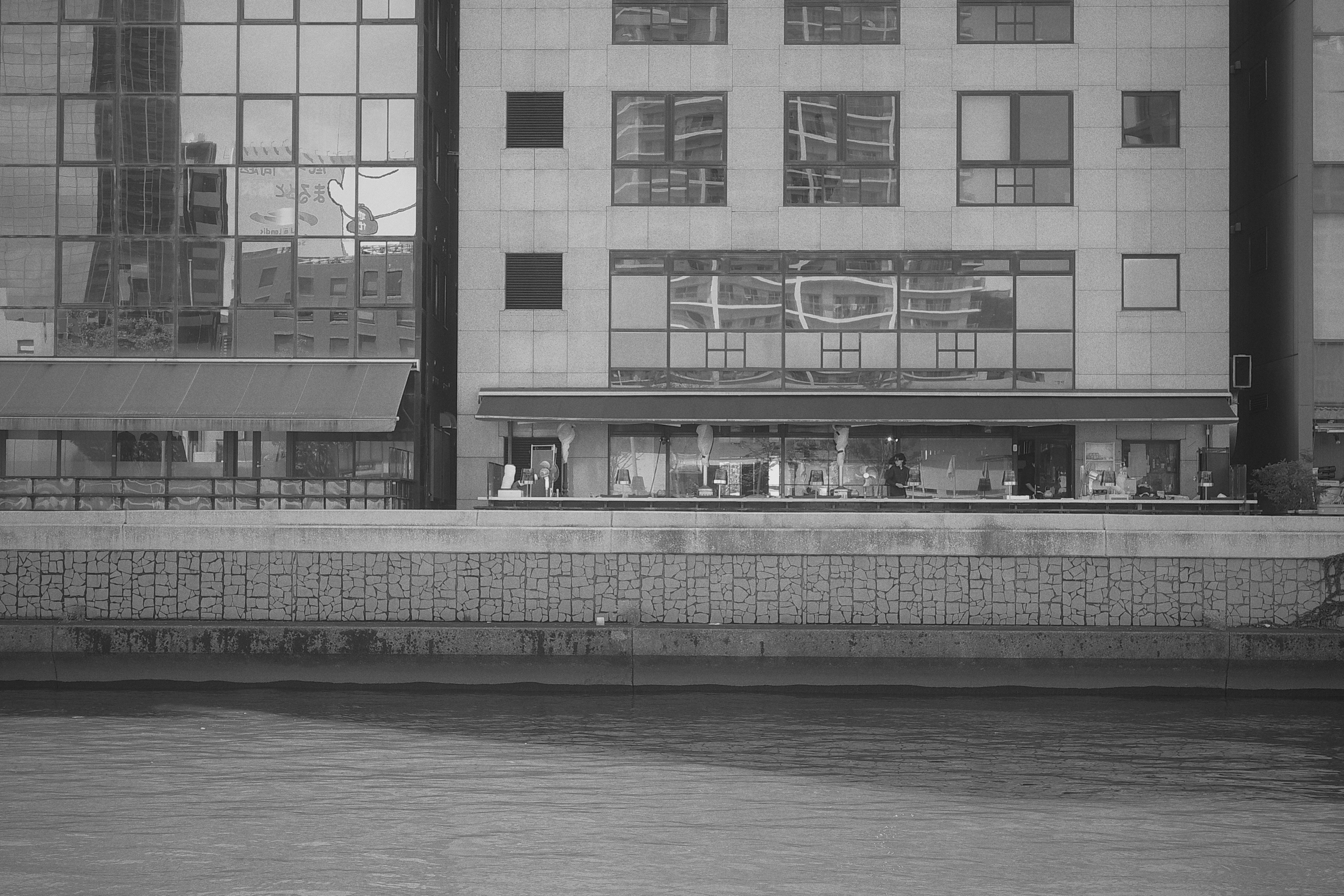 Facciata di un edificio moderno lungo il fiume con riflessi sull'acqua