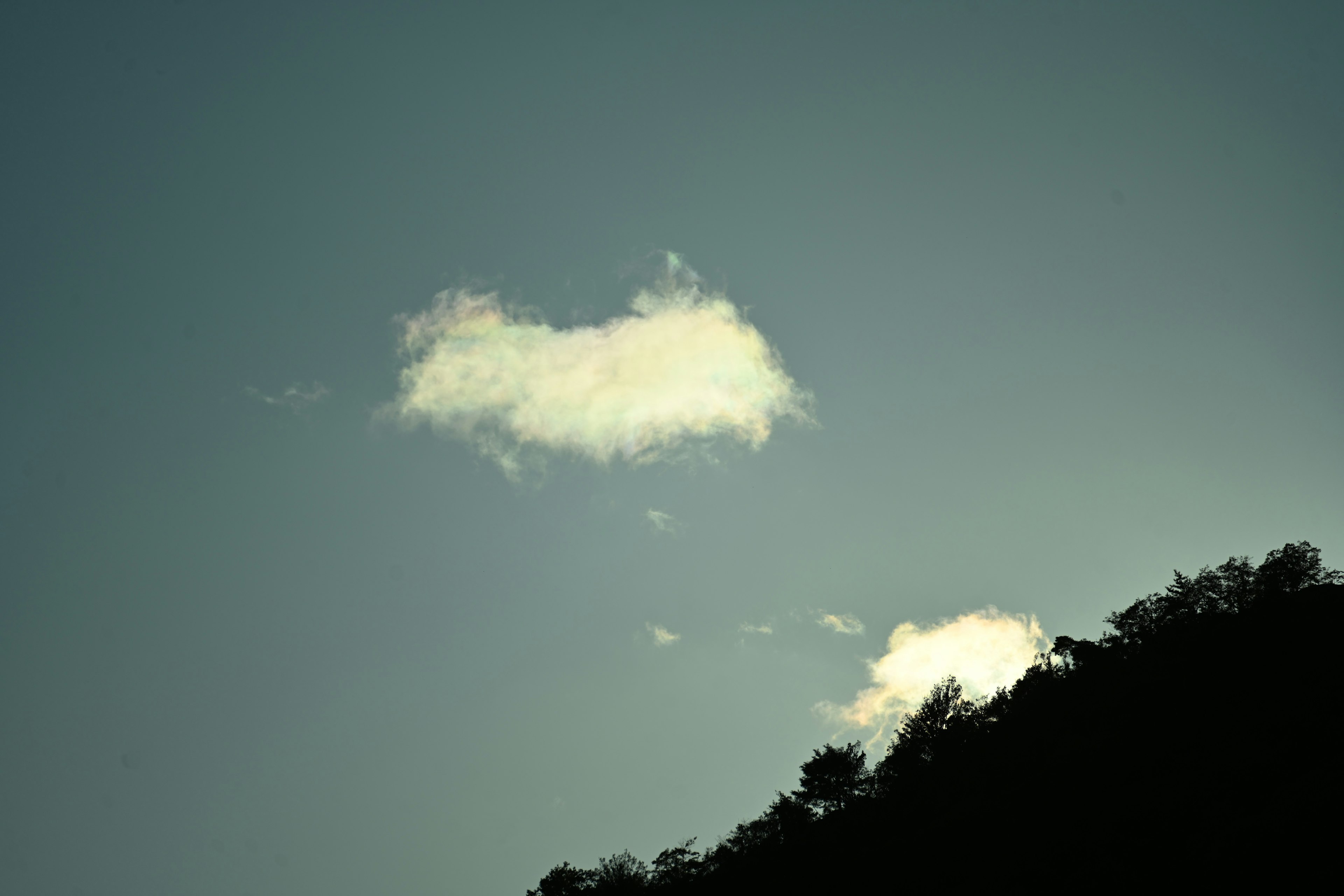 青い空の中に浮かぶ白い雲と山のシルエット