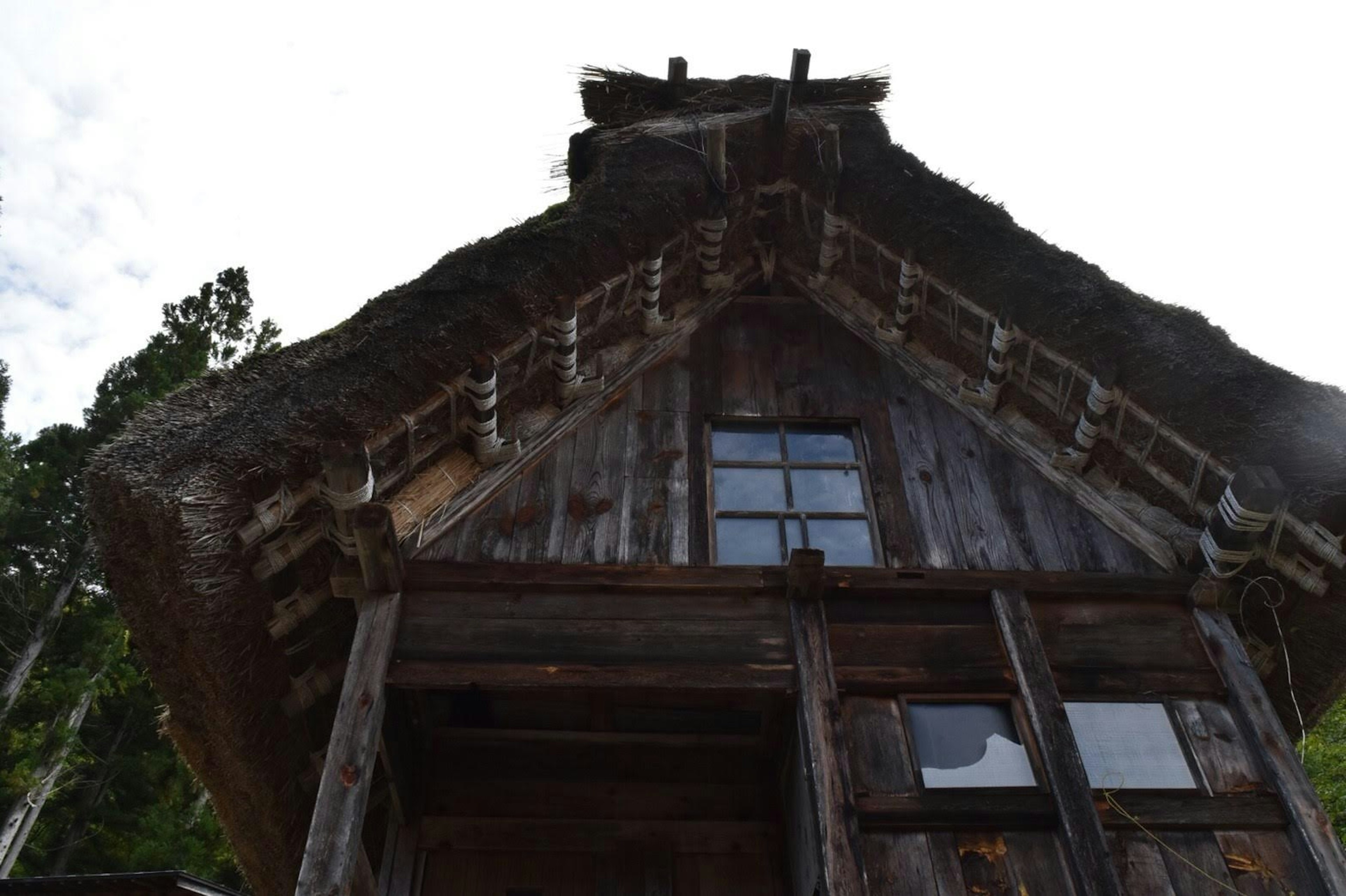 Image of a traditional Japanese gassho-zukuri house viewed from below focusing on the thatched roof