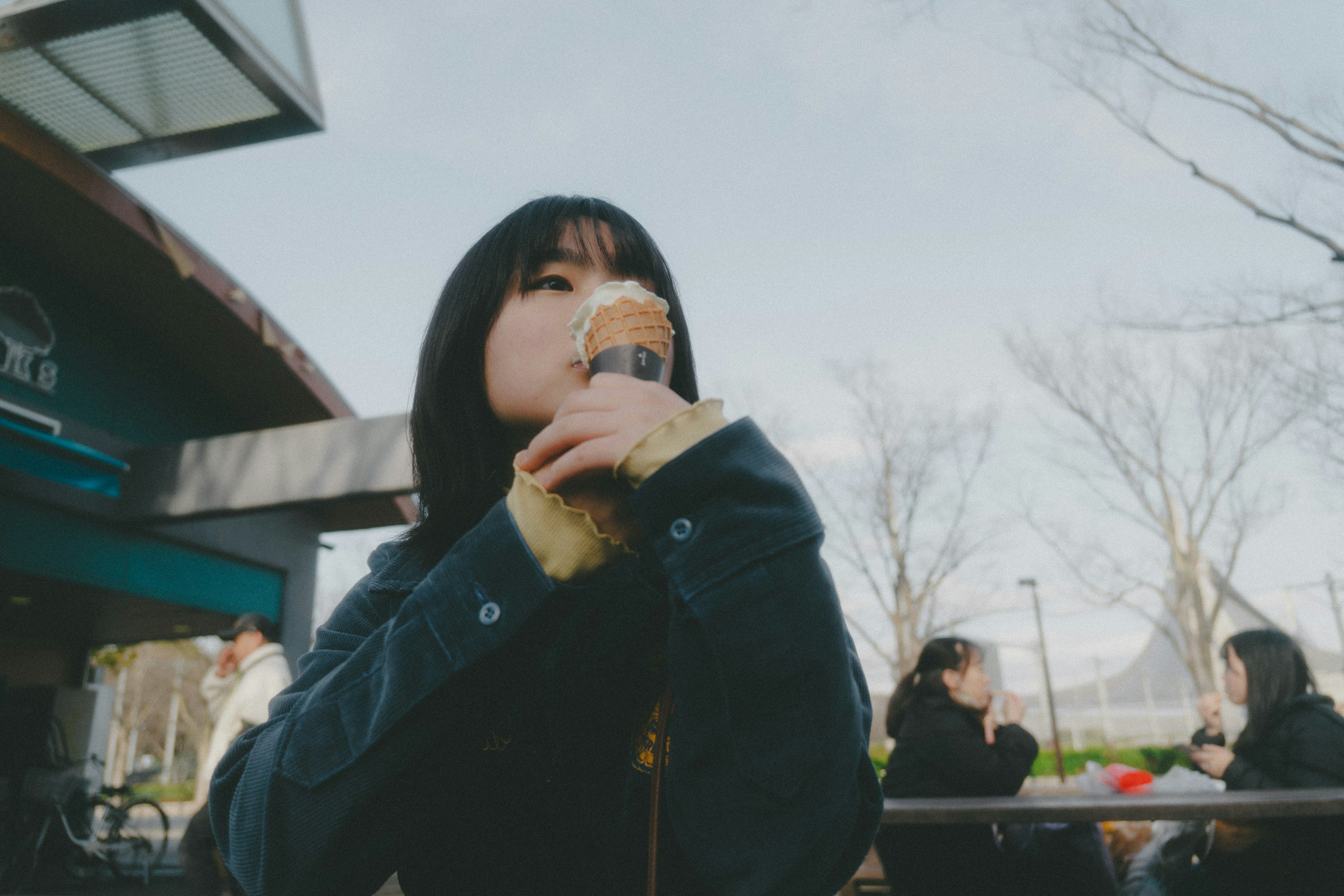 女性在公園裡享受冰淇淋，背景中有其他人