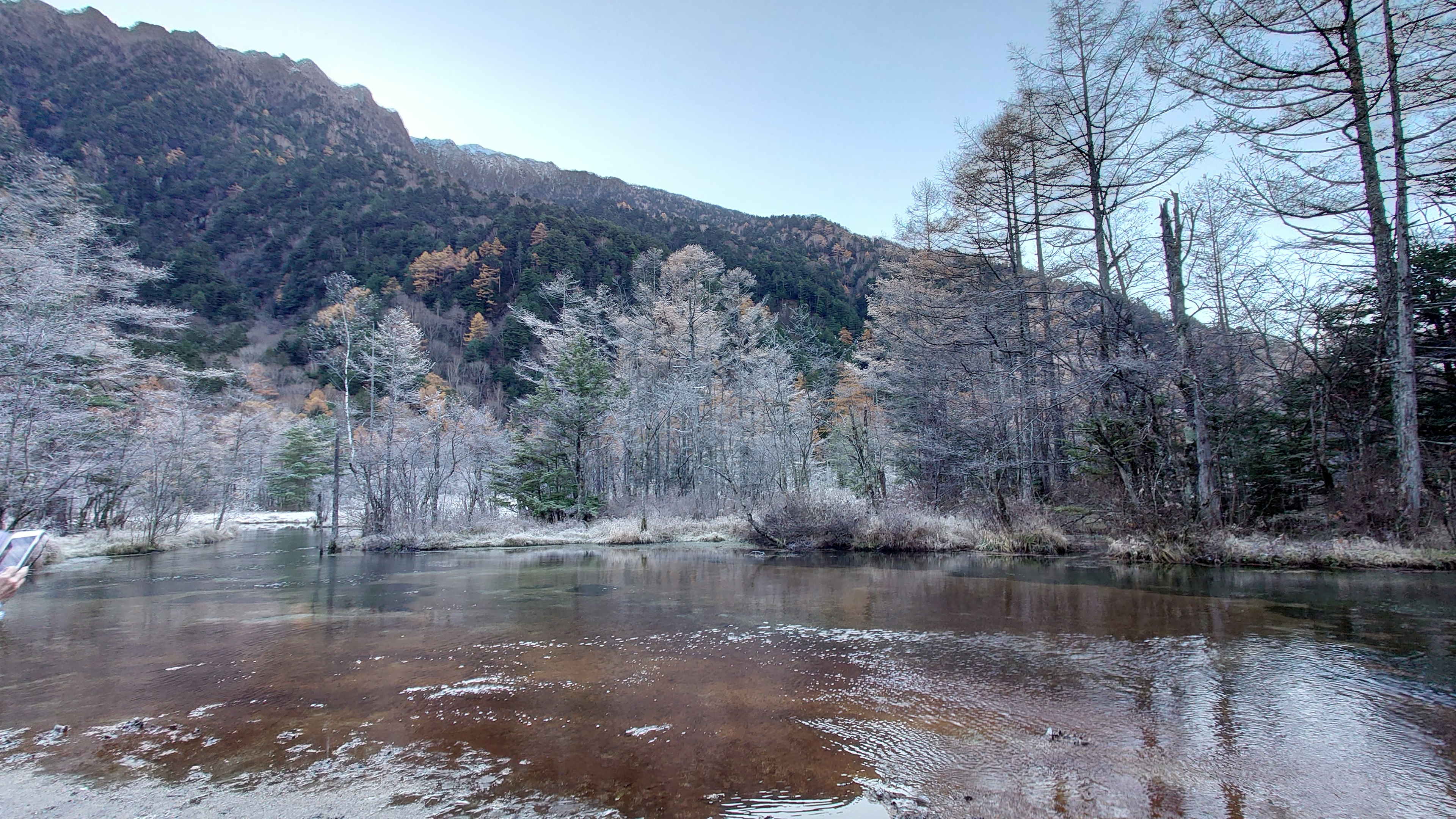 Ruhige Flusslandschaft mit Bäumen und Bergen im Hintergrund