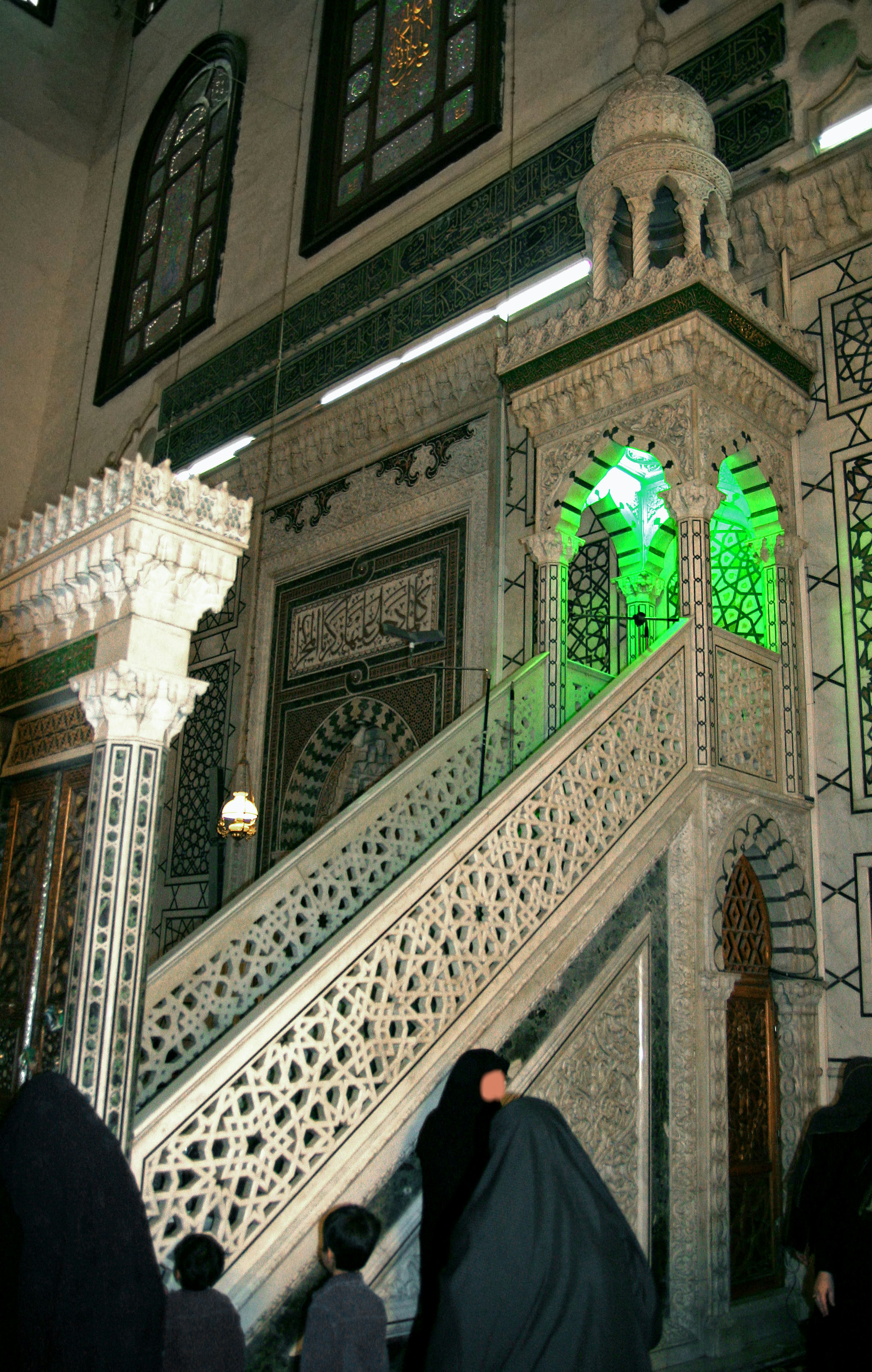 Interior de una mezquita con escalera decorativa y luz verde