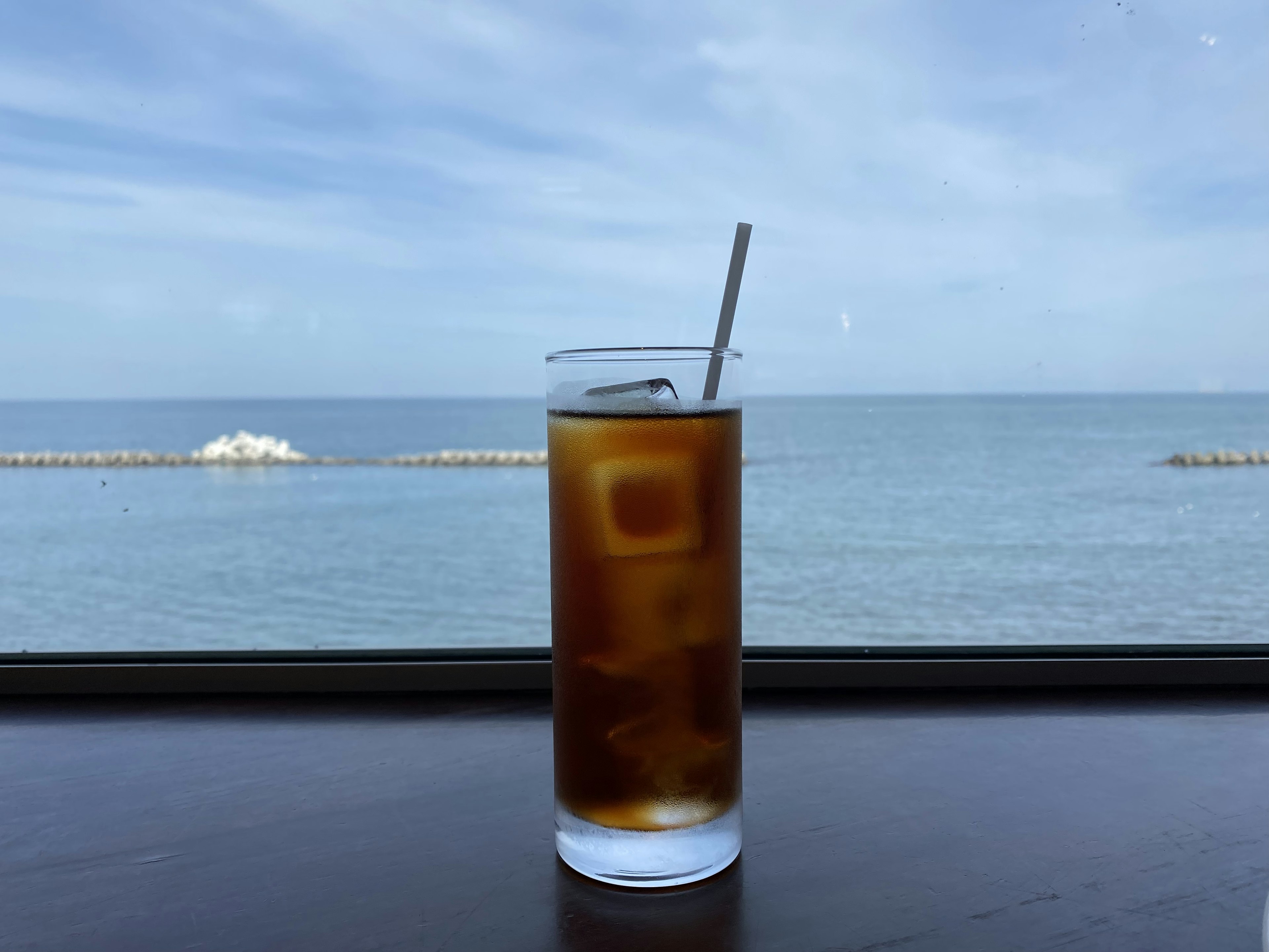 Glass of iced coffee with ocean view in the background