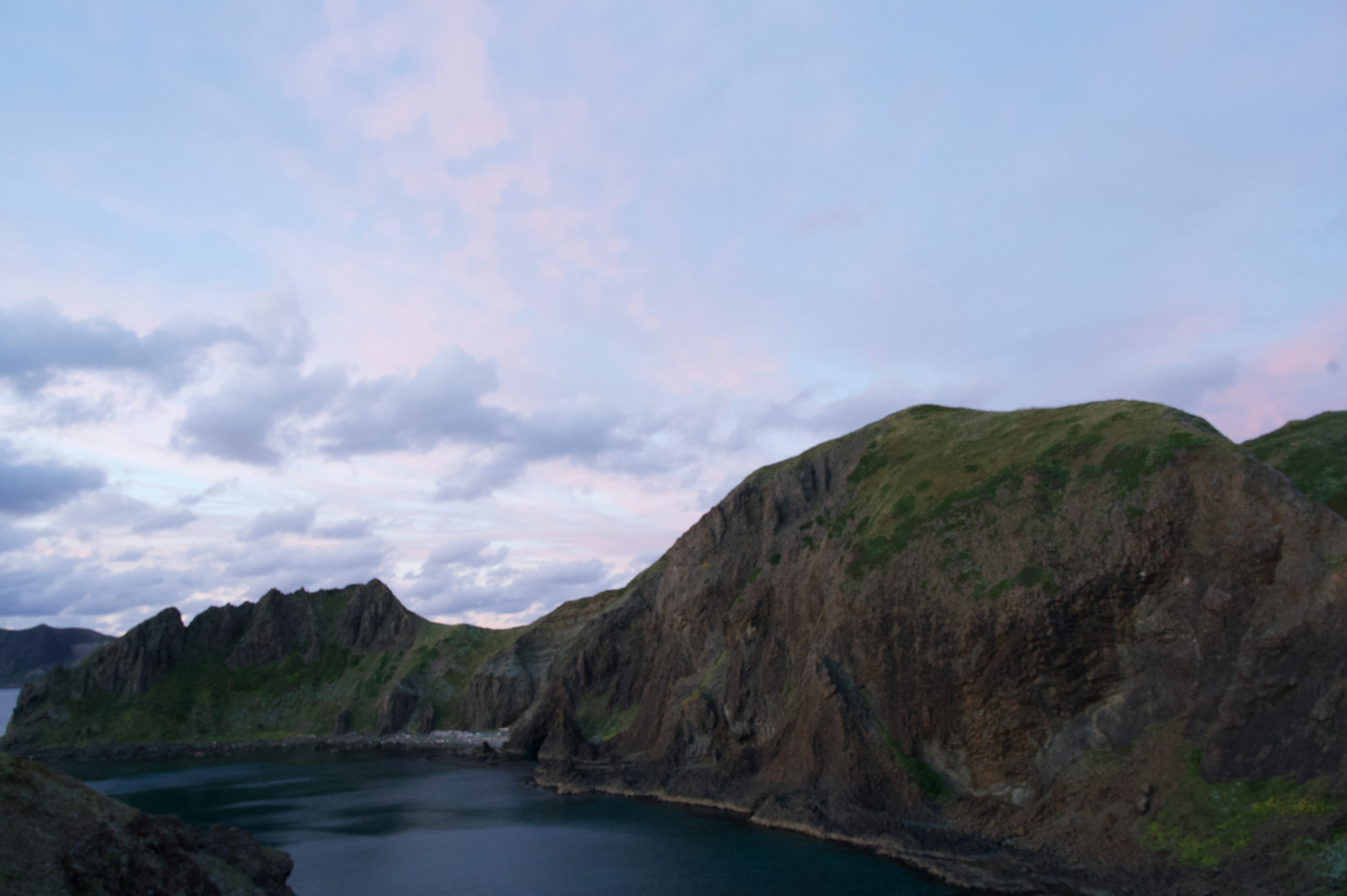 Vue pittoresque de collines verdoyantes entourant une mer bleue sous un ciel nuageux