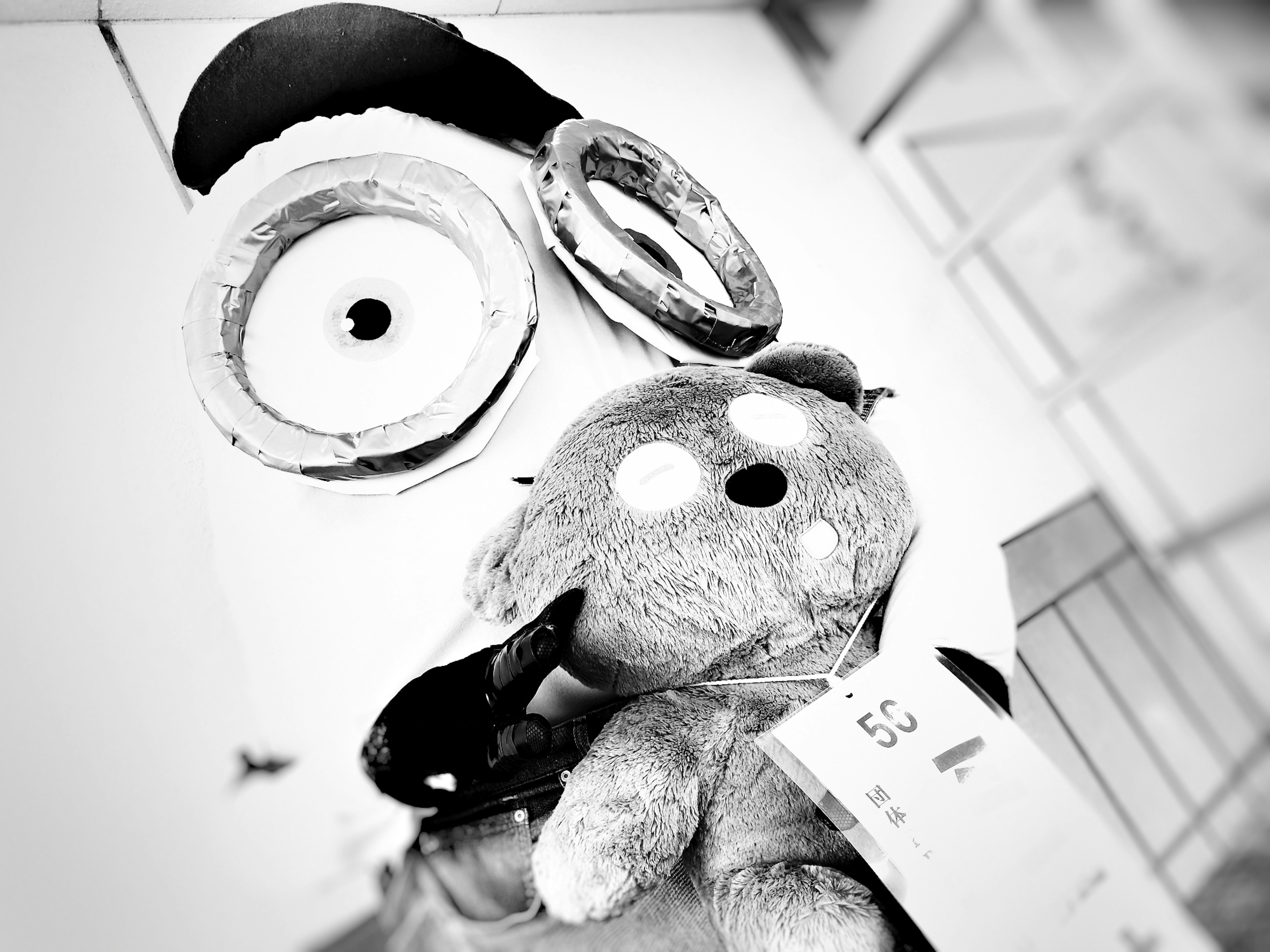 Black and white image of a Minion and a stuffed bear together