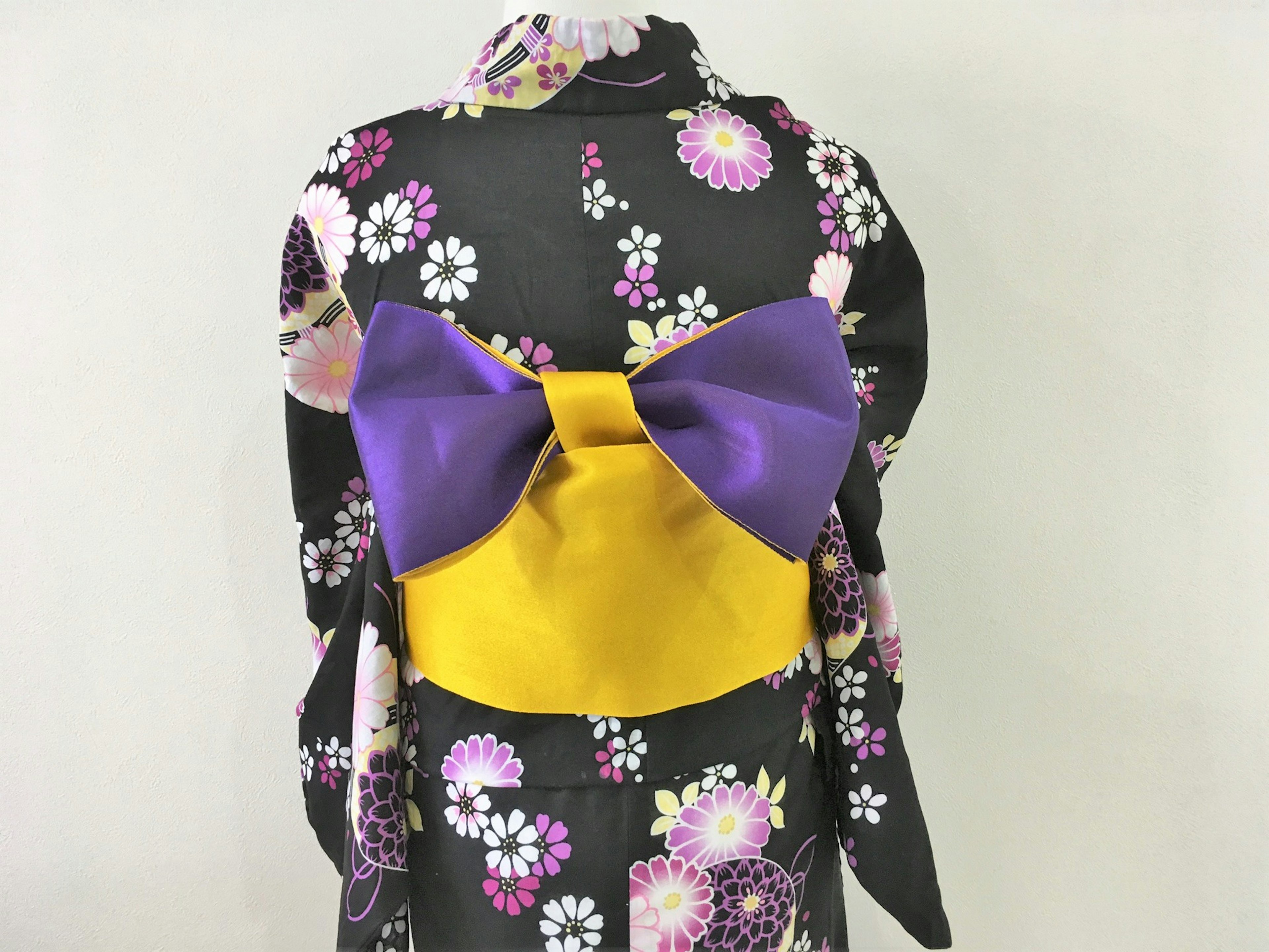 Back view of a kimono featuring a large purple and yellow bow