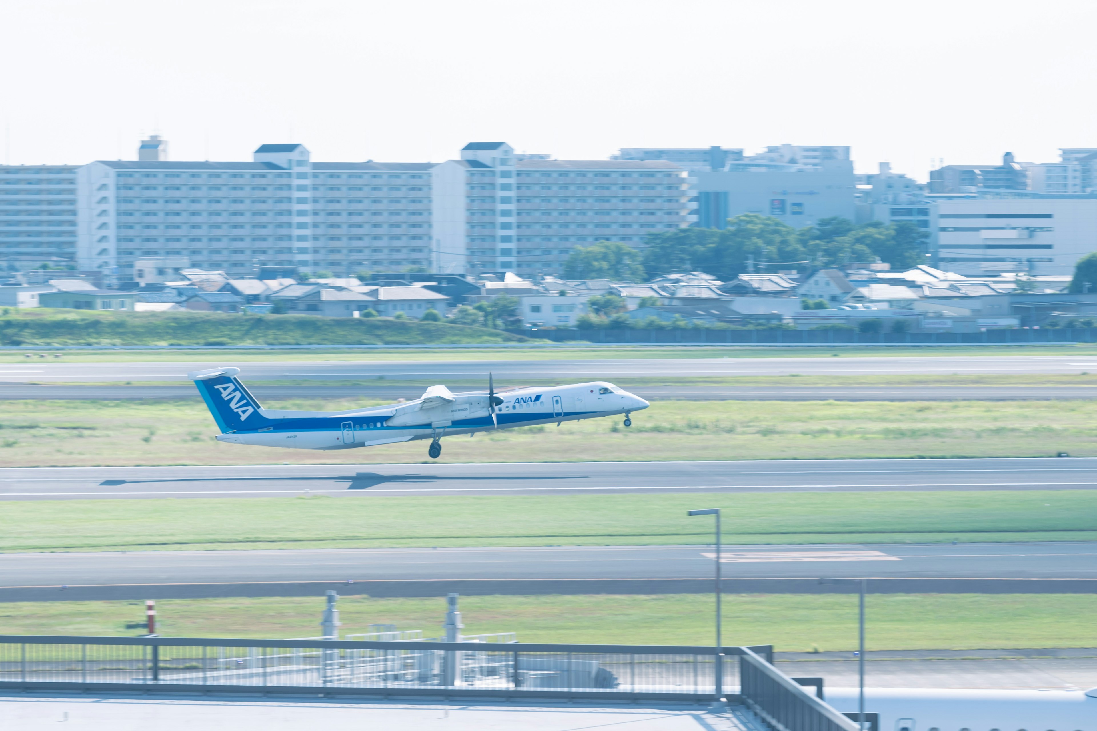 Small airplane landing on runway with city in background