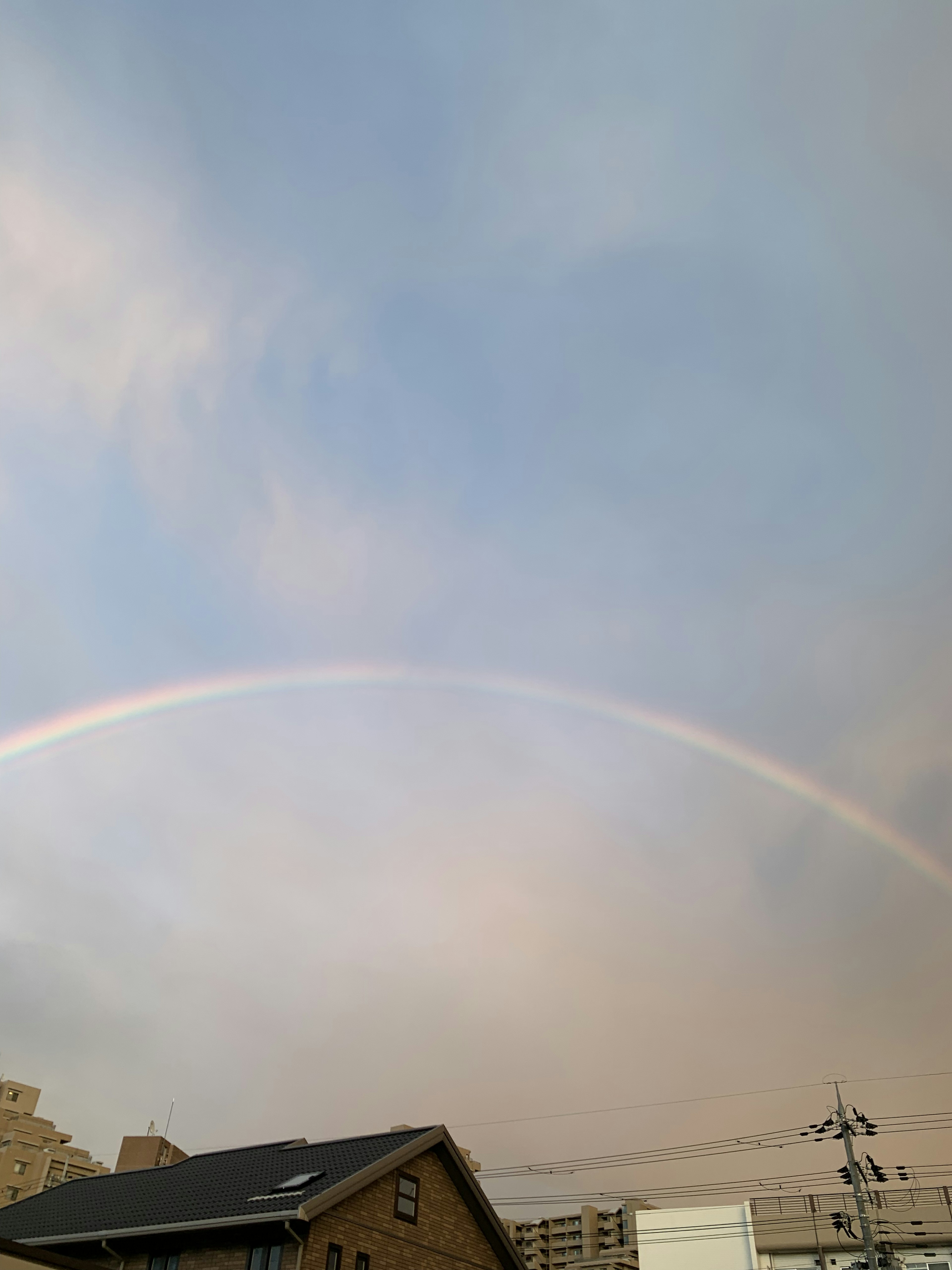 Un arc-en-ciel dans un ciel bleu avec des silhouettes de bâtiments