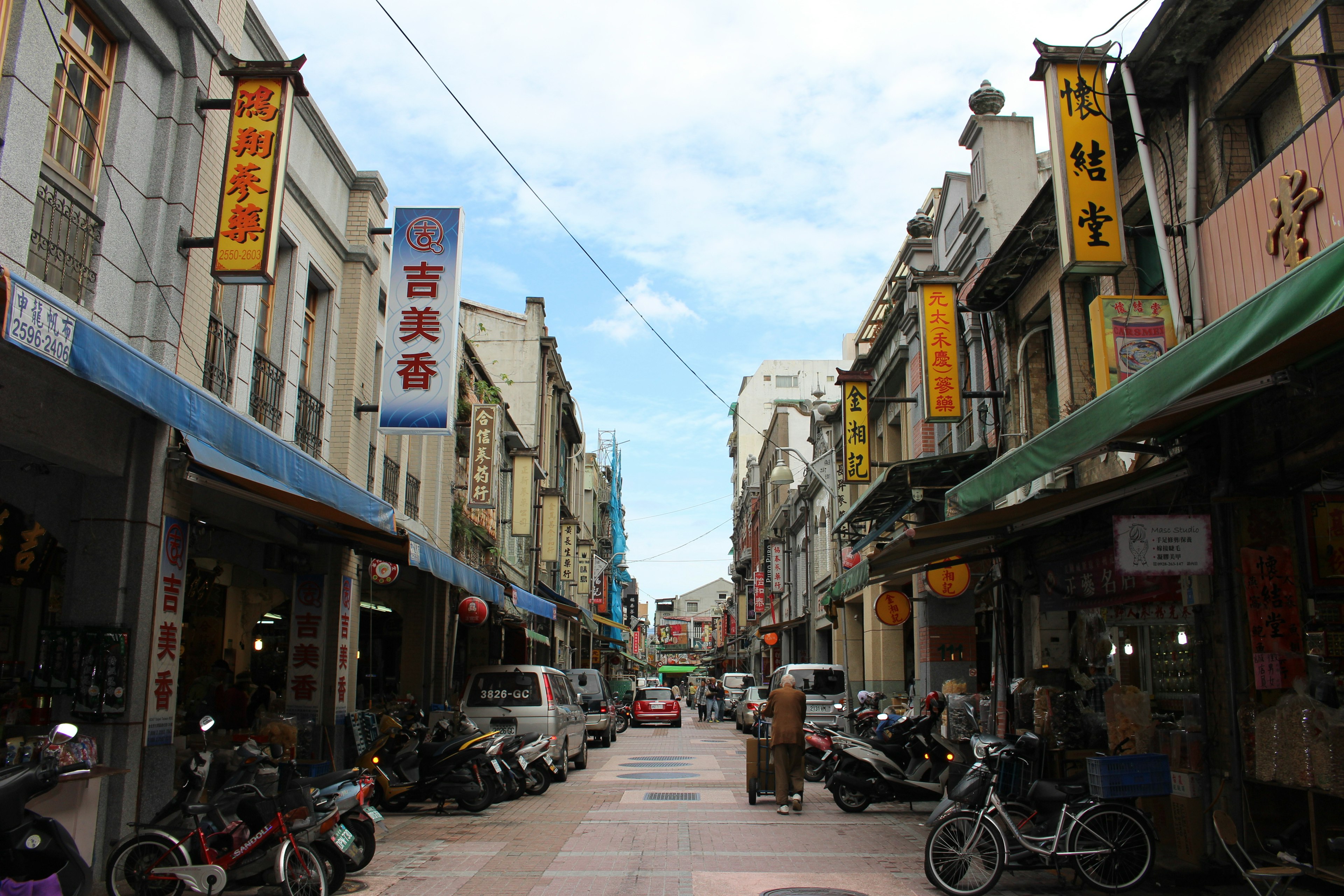 Bustling street lined with shops and parked motorcycles