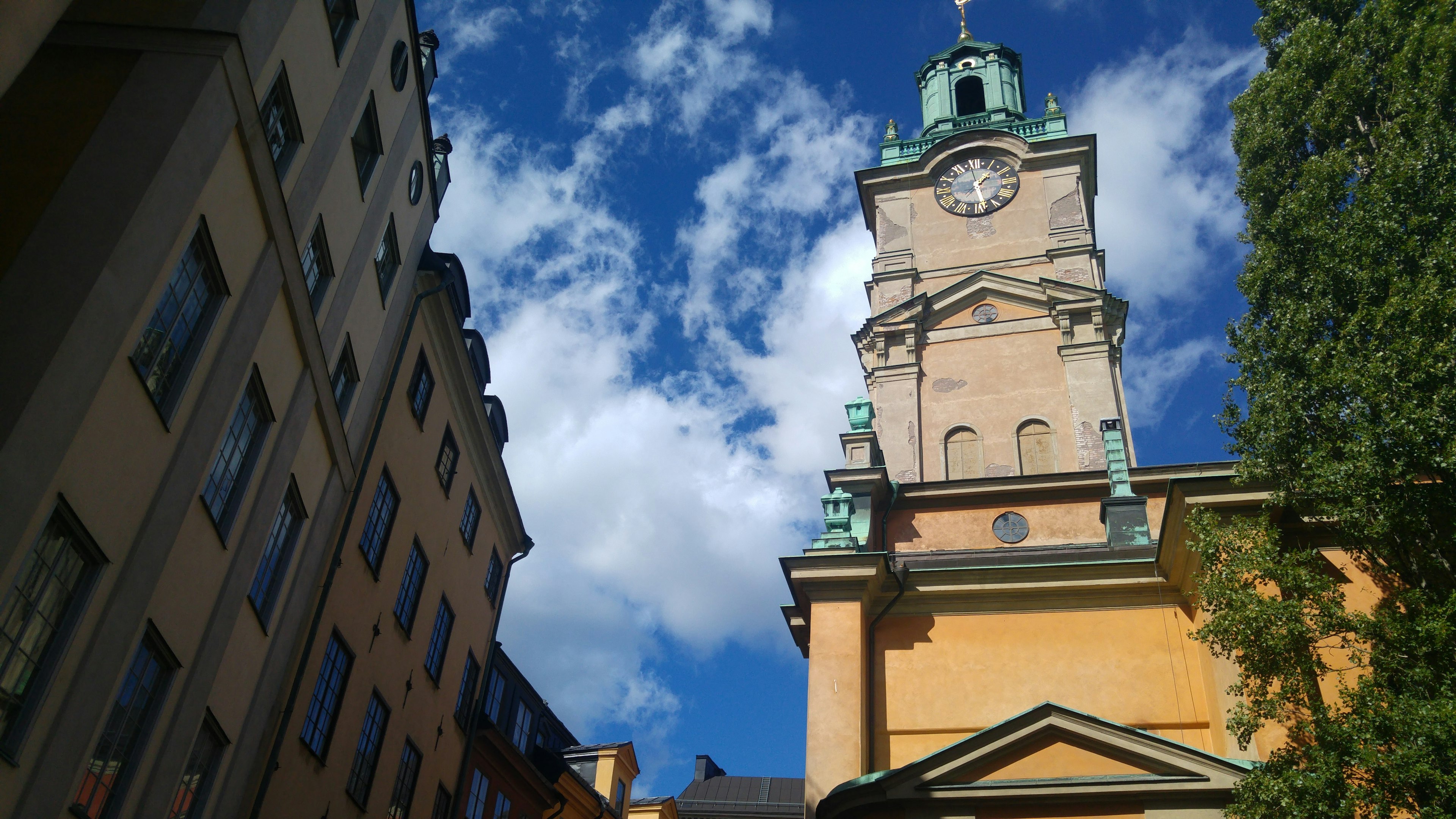 Clock tower against a blue sky with clouds and surrounding buildings