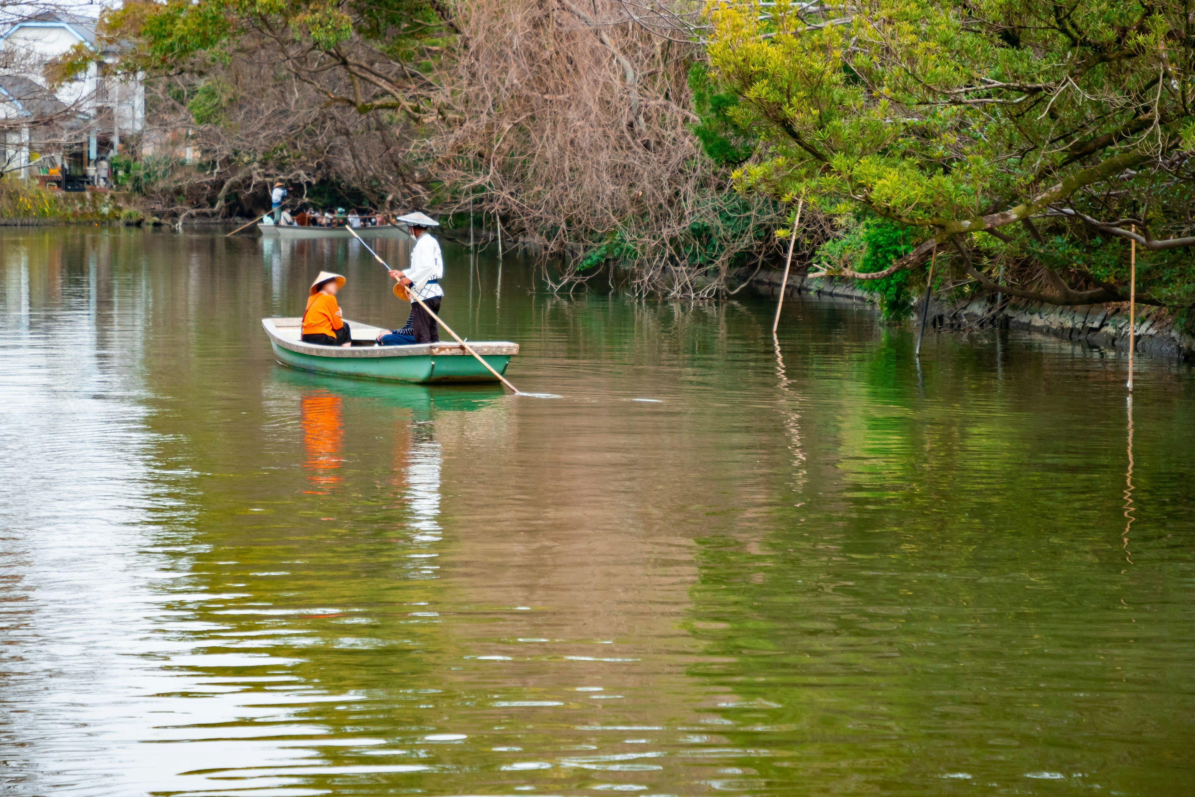 Deux pêcheurs dans un petit bateau rament sur une rivière entourée de verdure