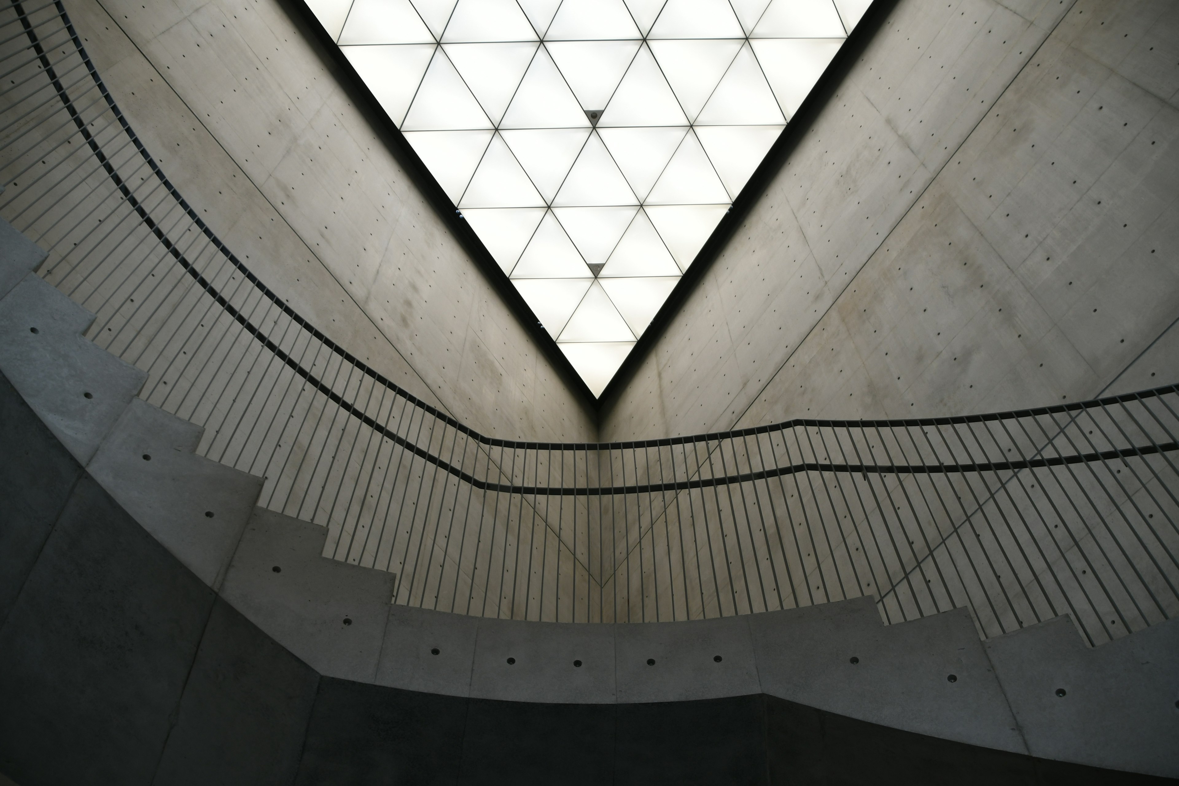 Interior of a modern building featuring concrete stairs and a triangular skylight