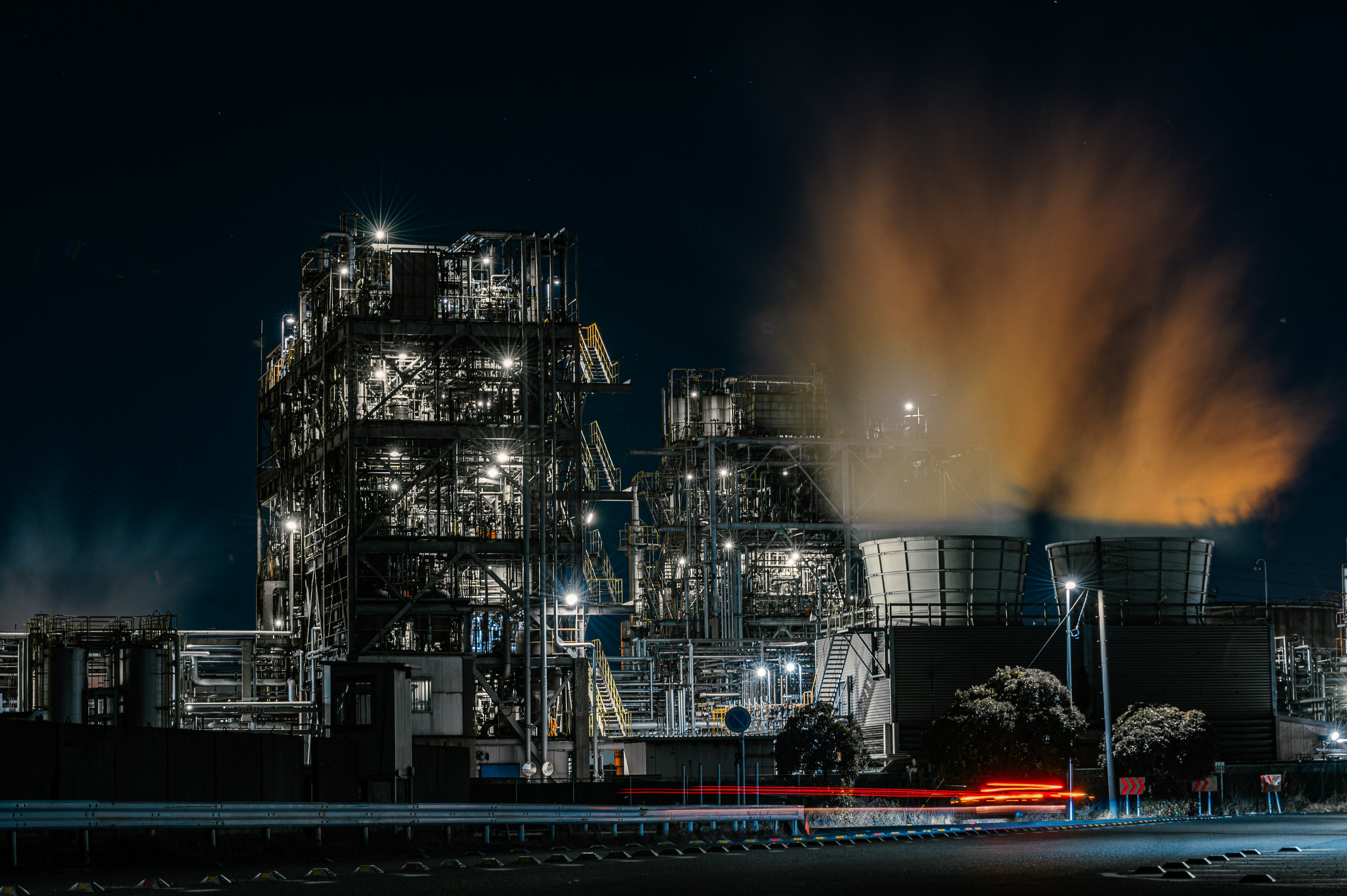 Nighttime industrial complex with smoke billowing from cooling towers