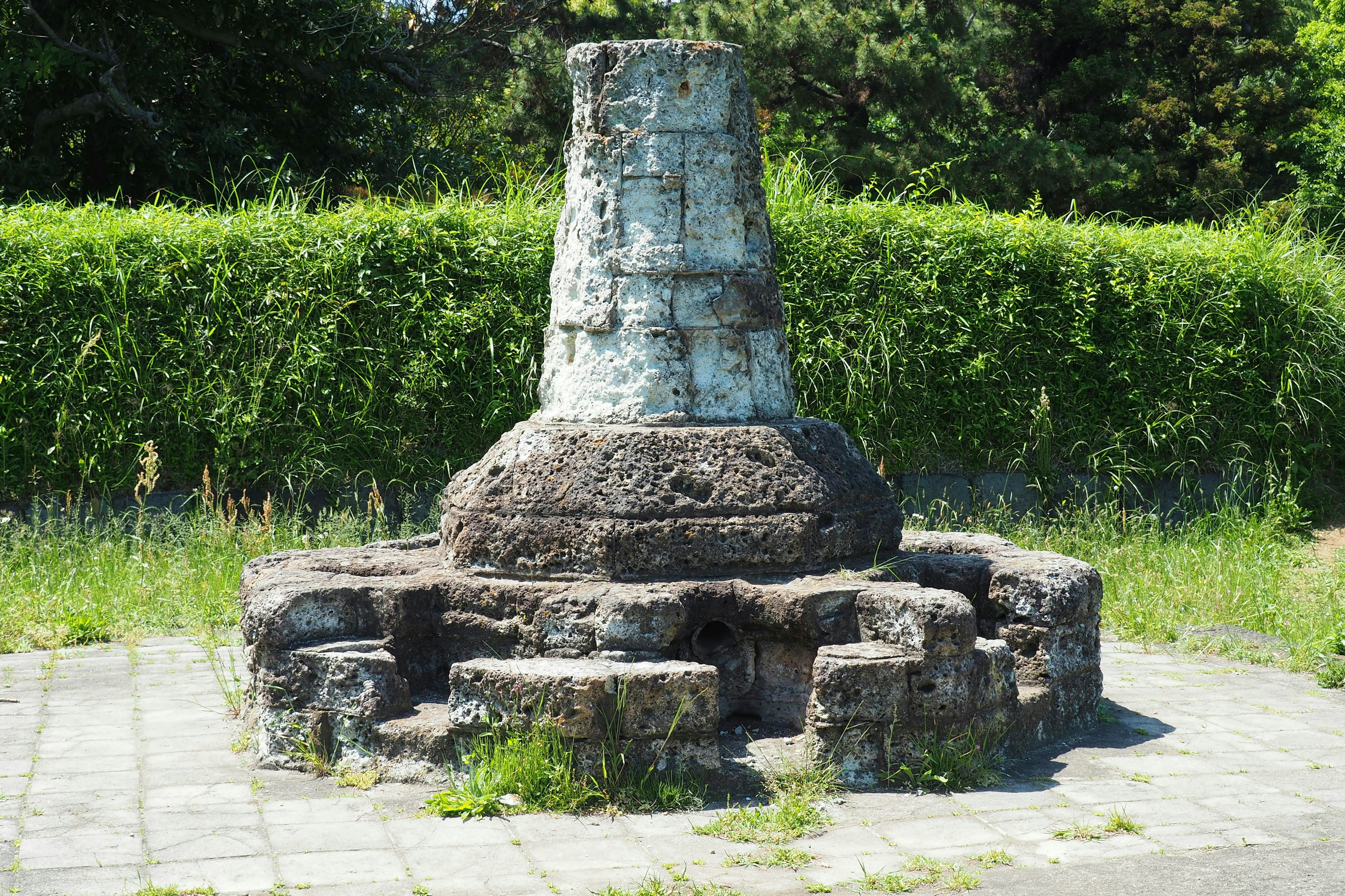 Ein antikes Steindenkmal, das von Gras in einem Park umgeben ist