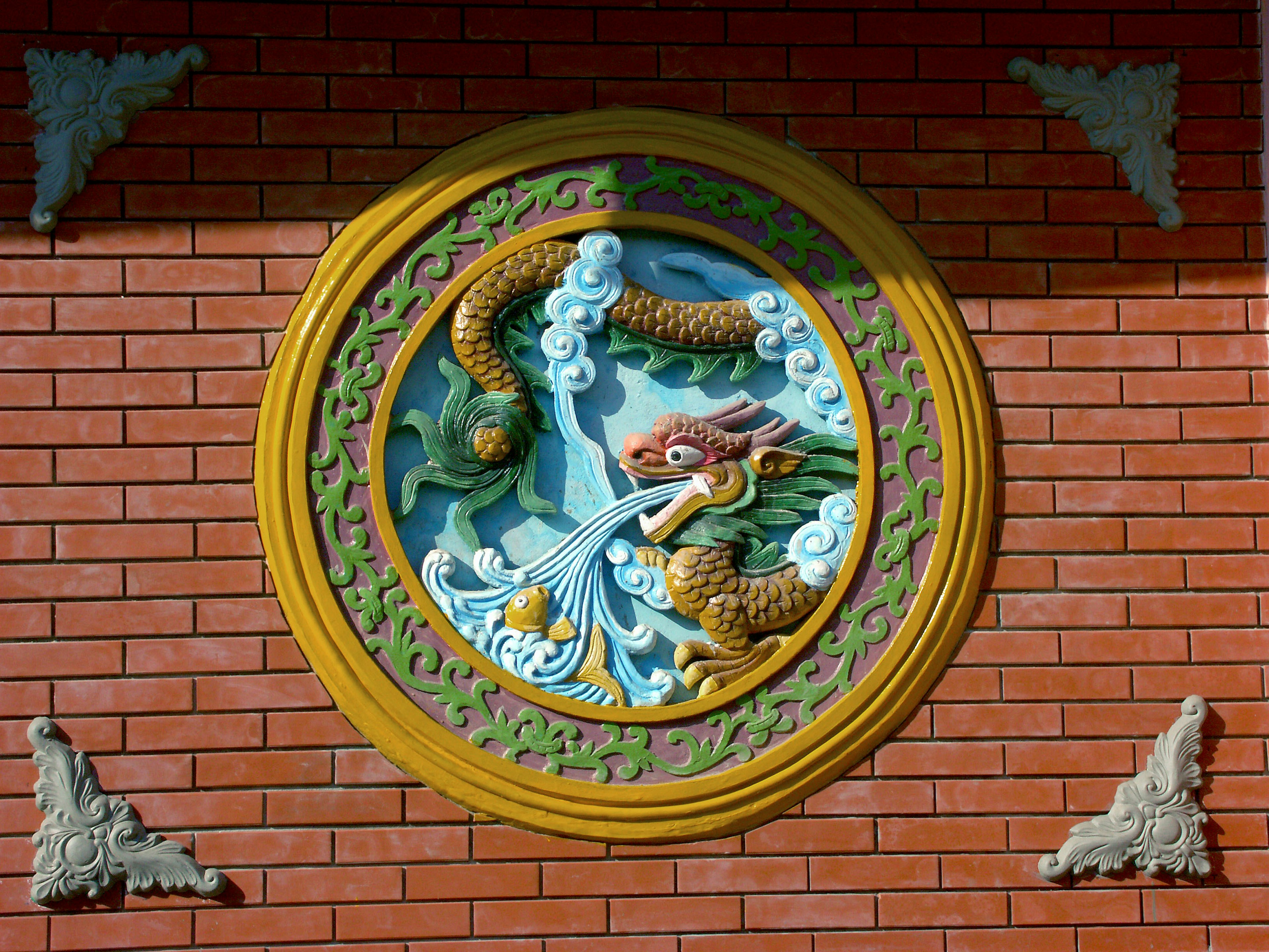 Una scultura decorativa di un drago che spruzza acqua su un muro di mattoni rossi